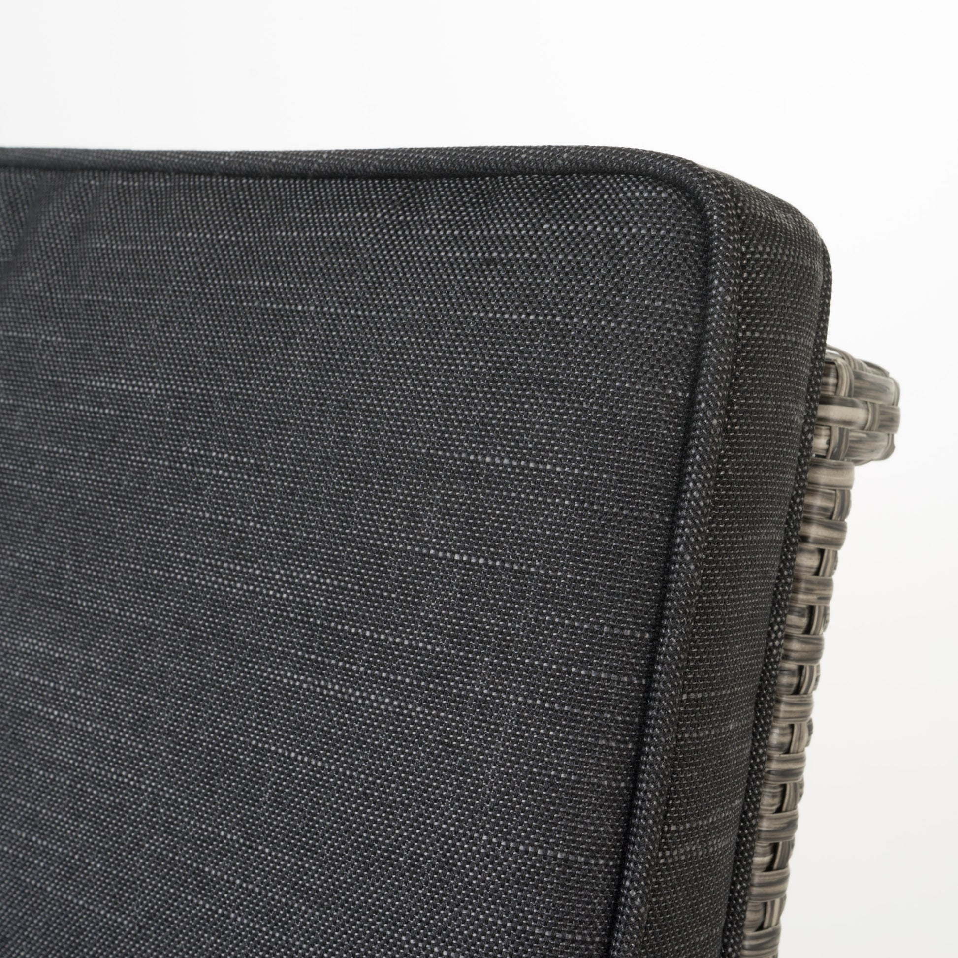 Closeup of a dark grey outdoor cushion with woven wicker side detail