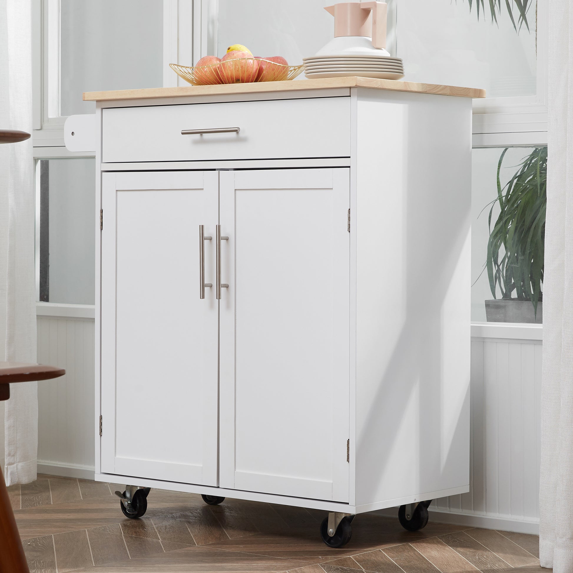 White kitchen cart with dual cabinet doors silver handles and a wooden top
