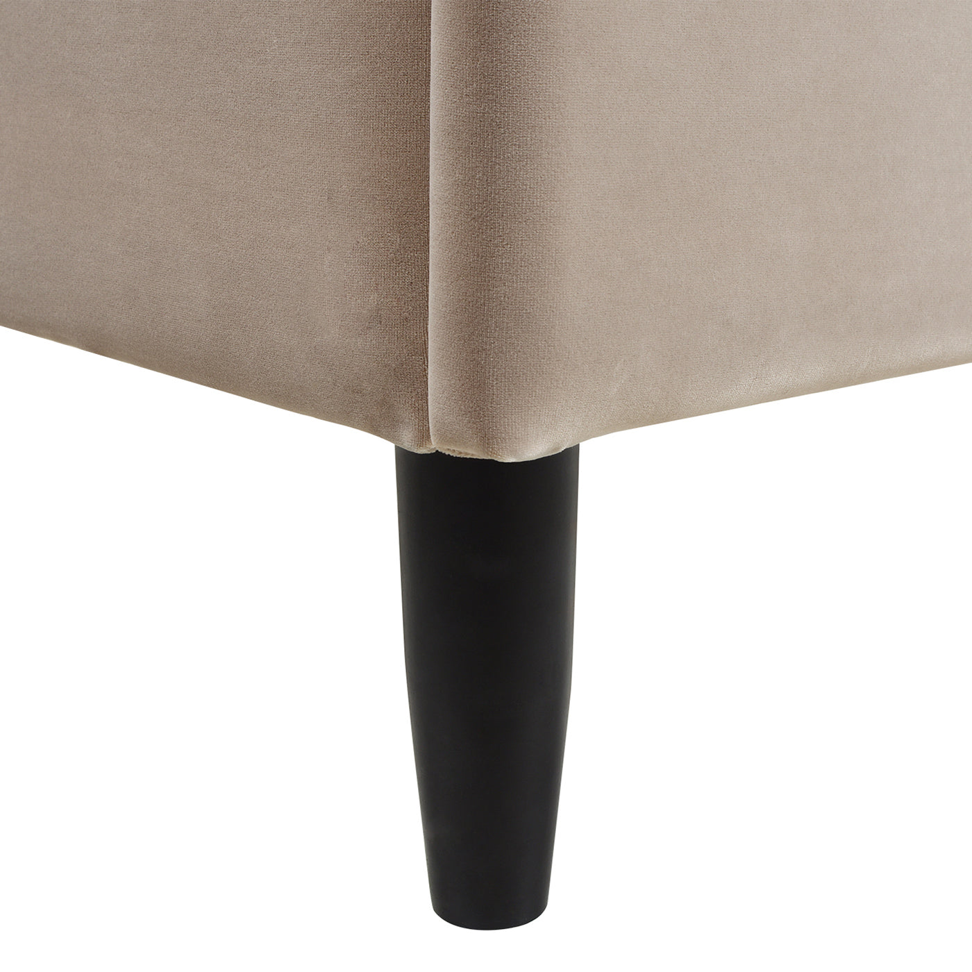 Tapered black leg of a beige velvet upholstered bed frame