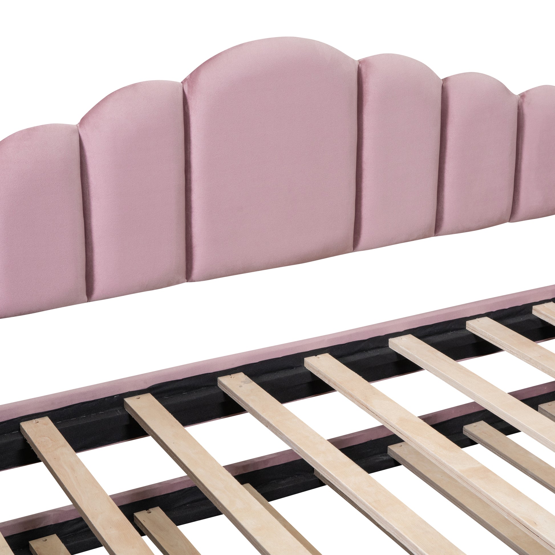 Pink velvet scalloped headboard with wooden bed slats visible