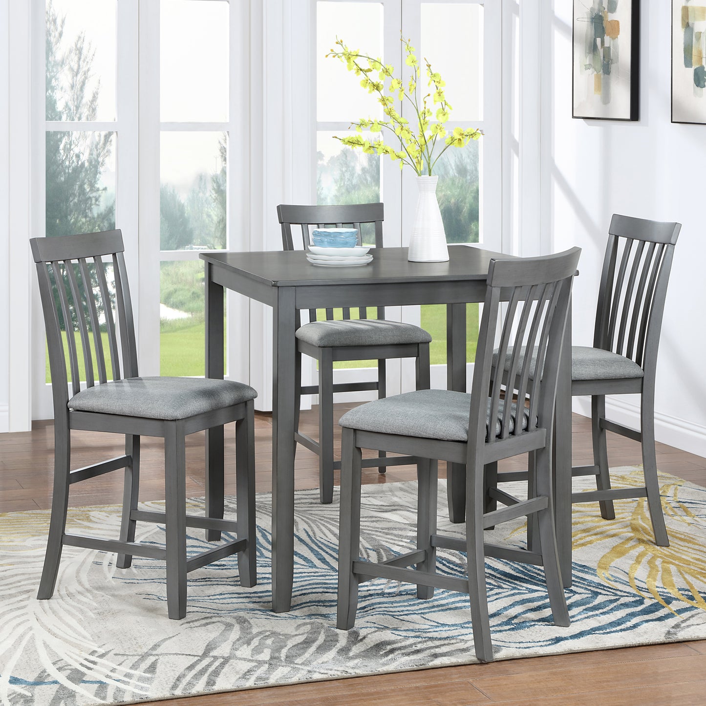 Gray wood counter height table set with upholstered gray stools by a window