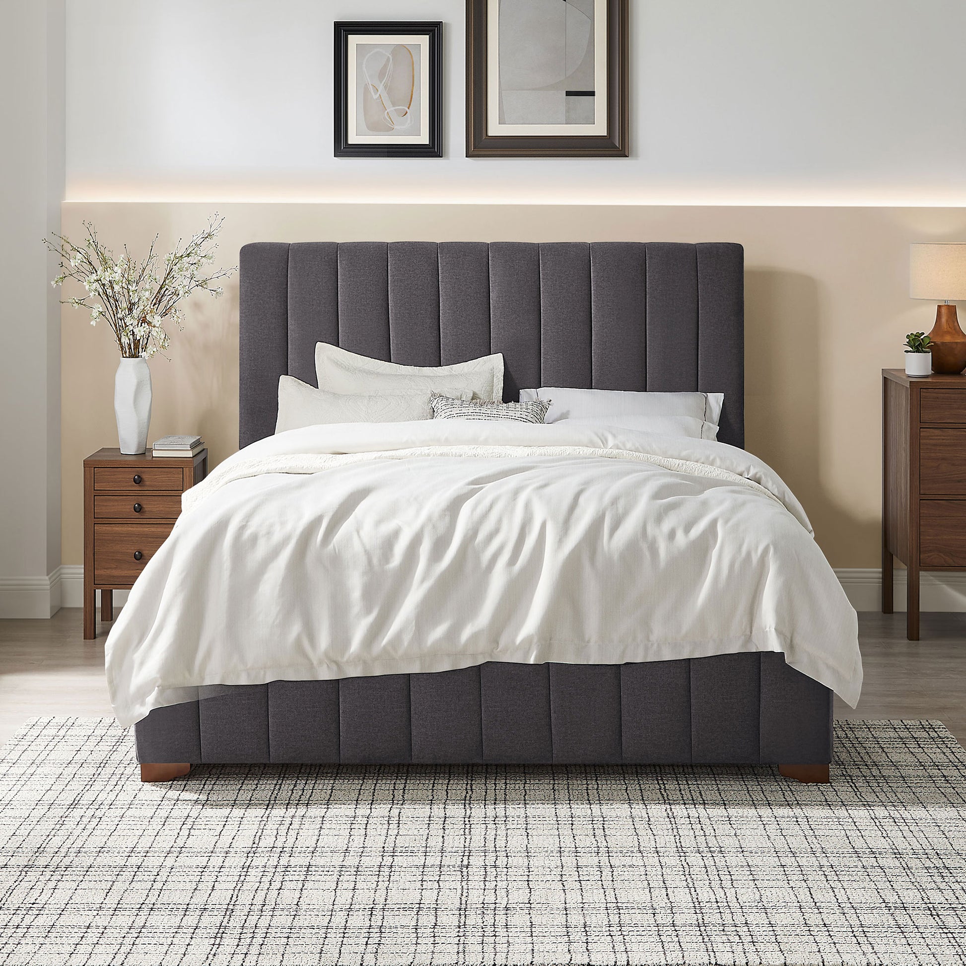 Charcoal grey upholstered platform bed with vertical tufting and white linens