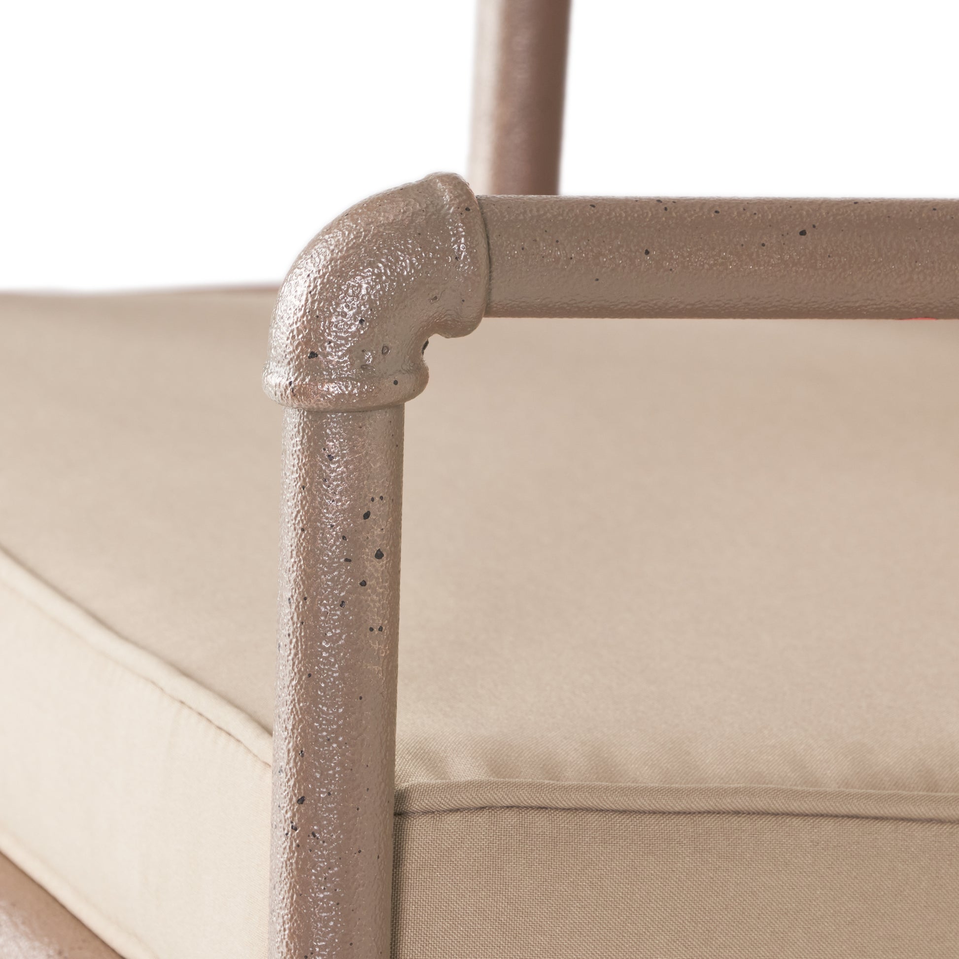 Tan outdoor chair frame detail with textured pipe armrest