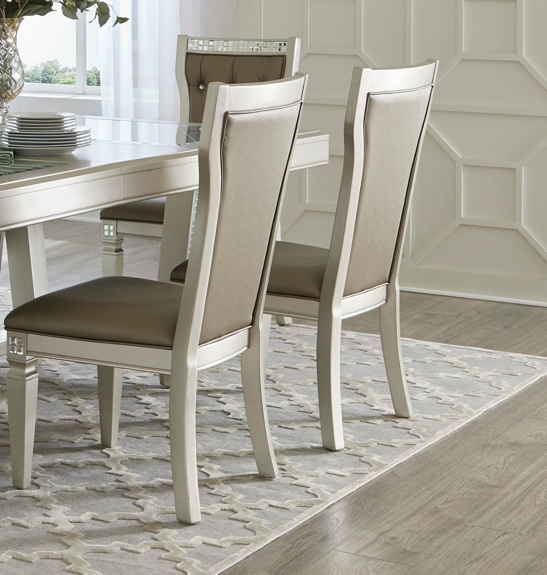 Two upholstered dining chairs with cream frames and taupe seats