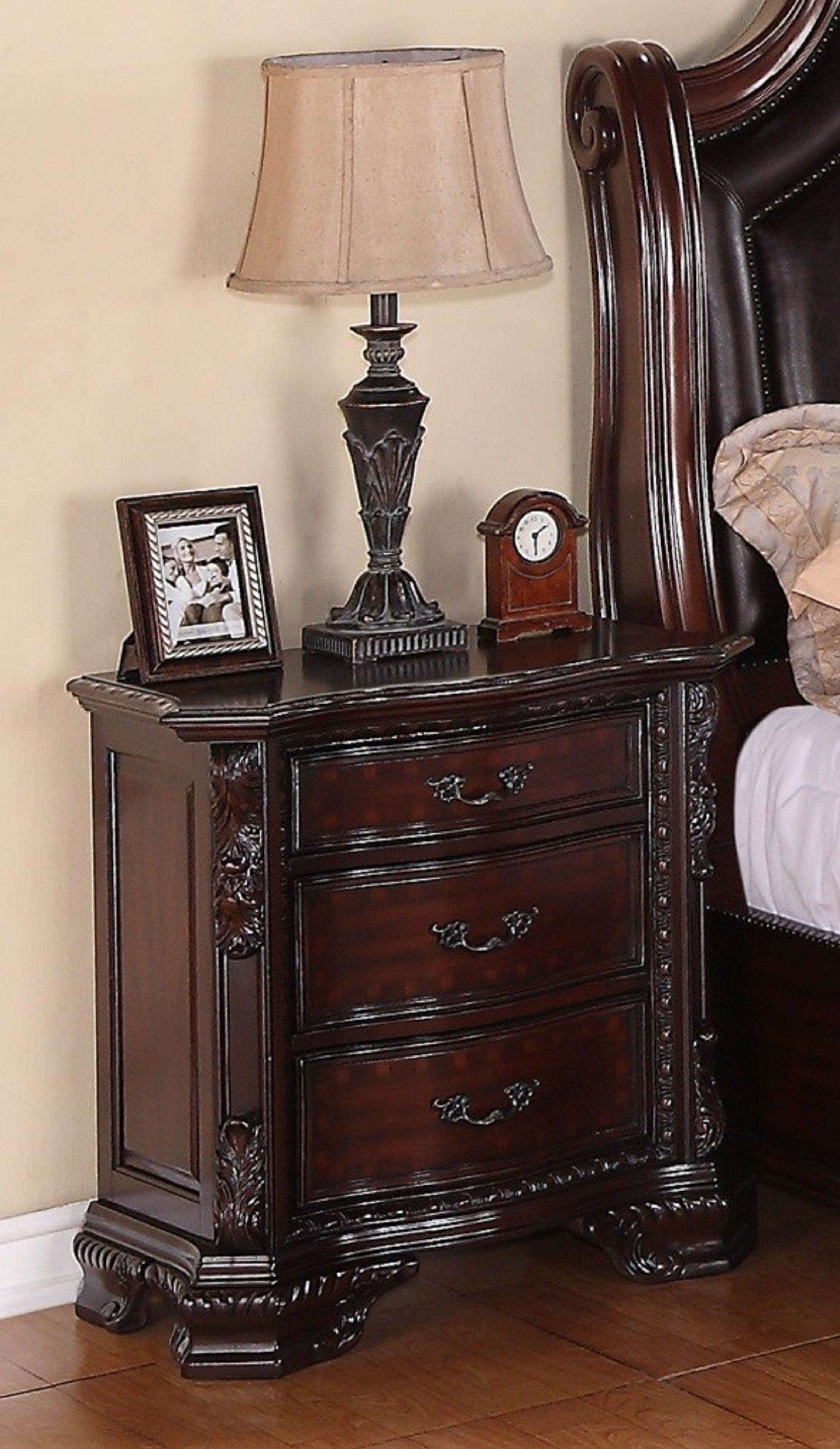 Ornate dark wood nightstand with three drawers and decorative carvings