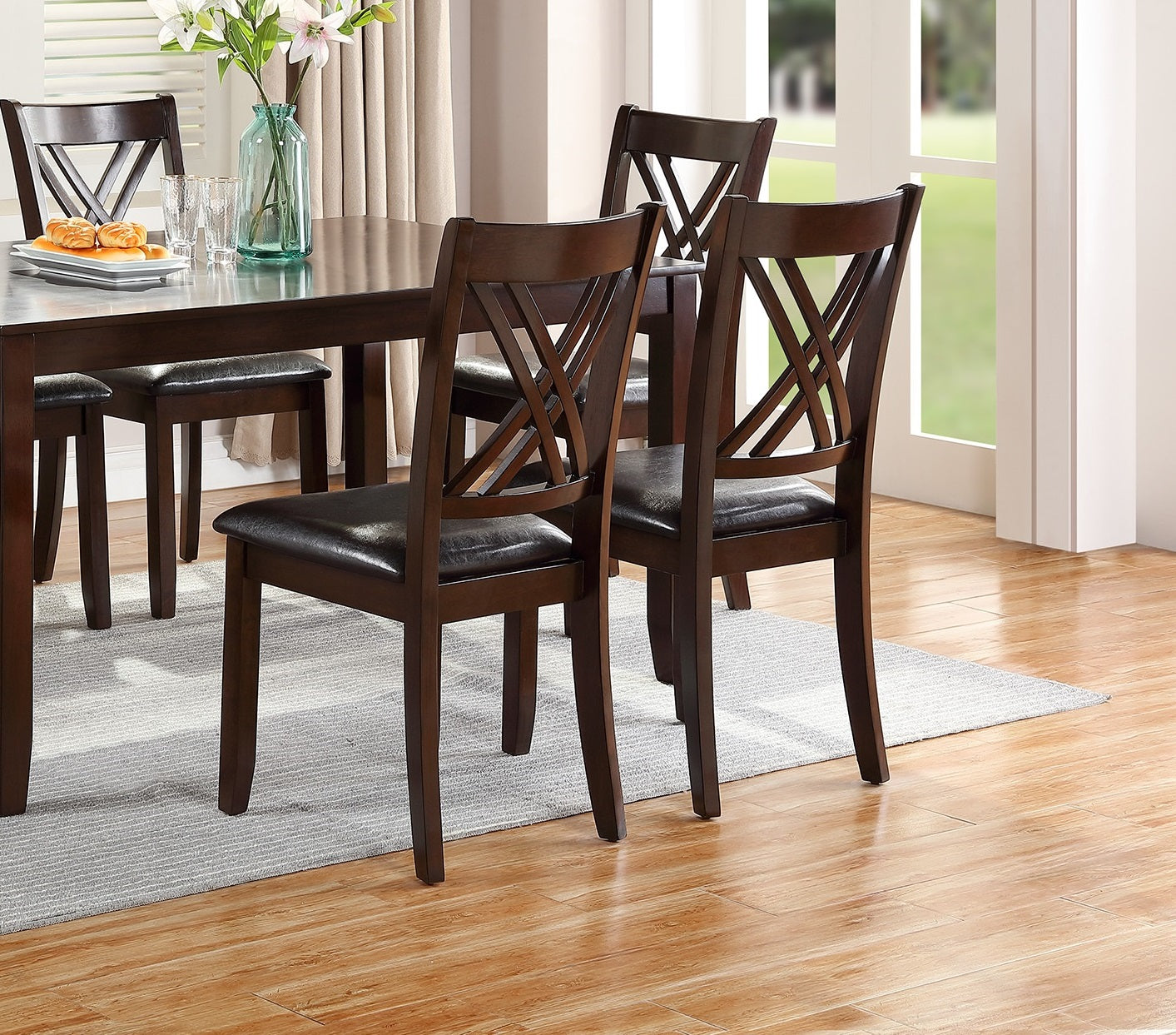 Dark brown wooden dining chairs with crisscross backs and leather seats