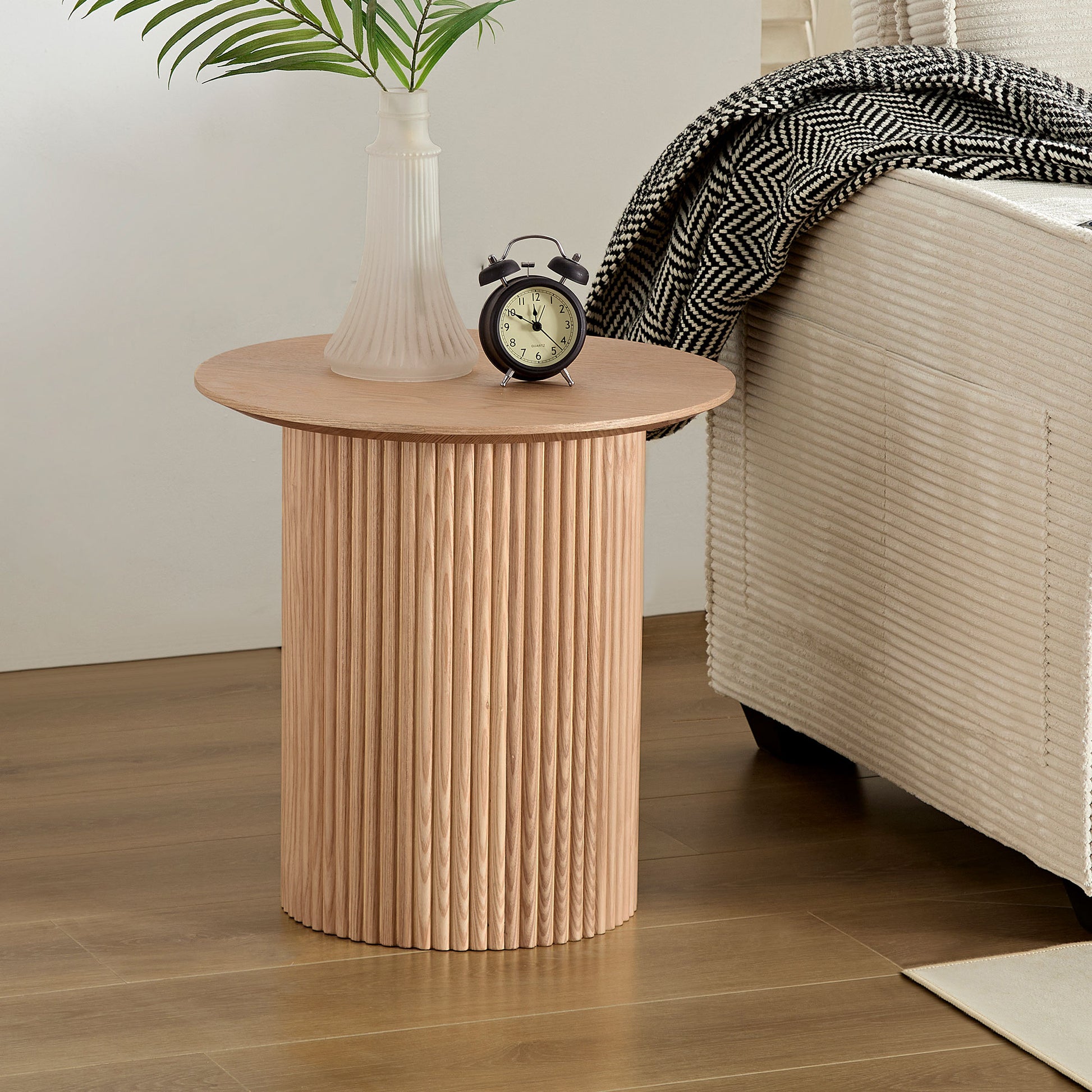 Light wood fluted drum side table with a round top beside a sofa