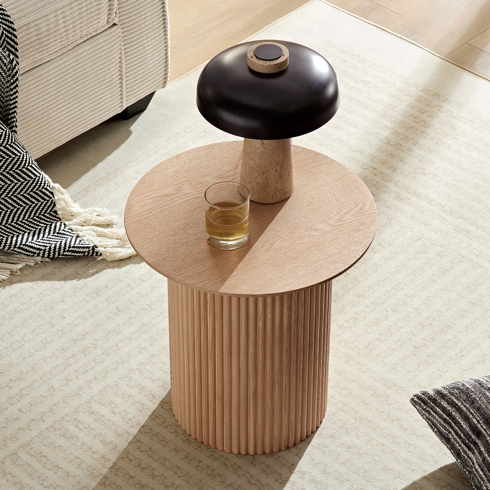 Round oak wood side table with fluted base and black mushroom lamp