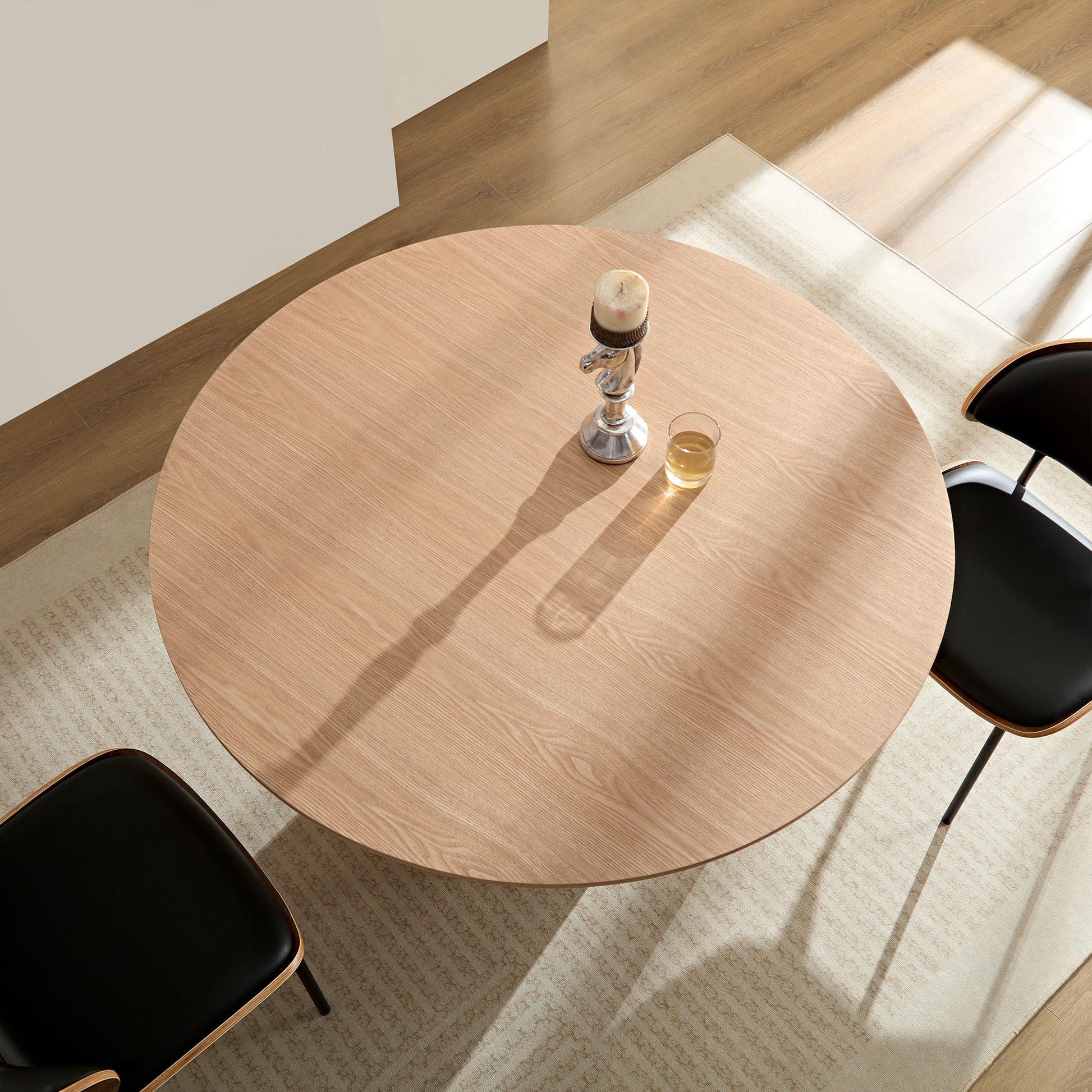 Round oak veneer dining table with black modern chairs