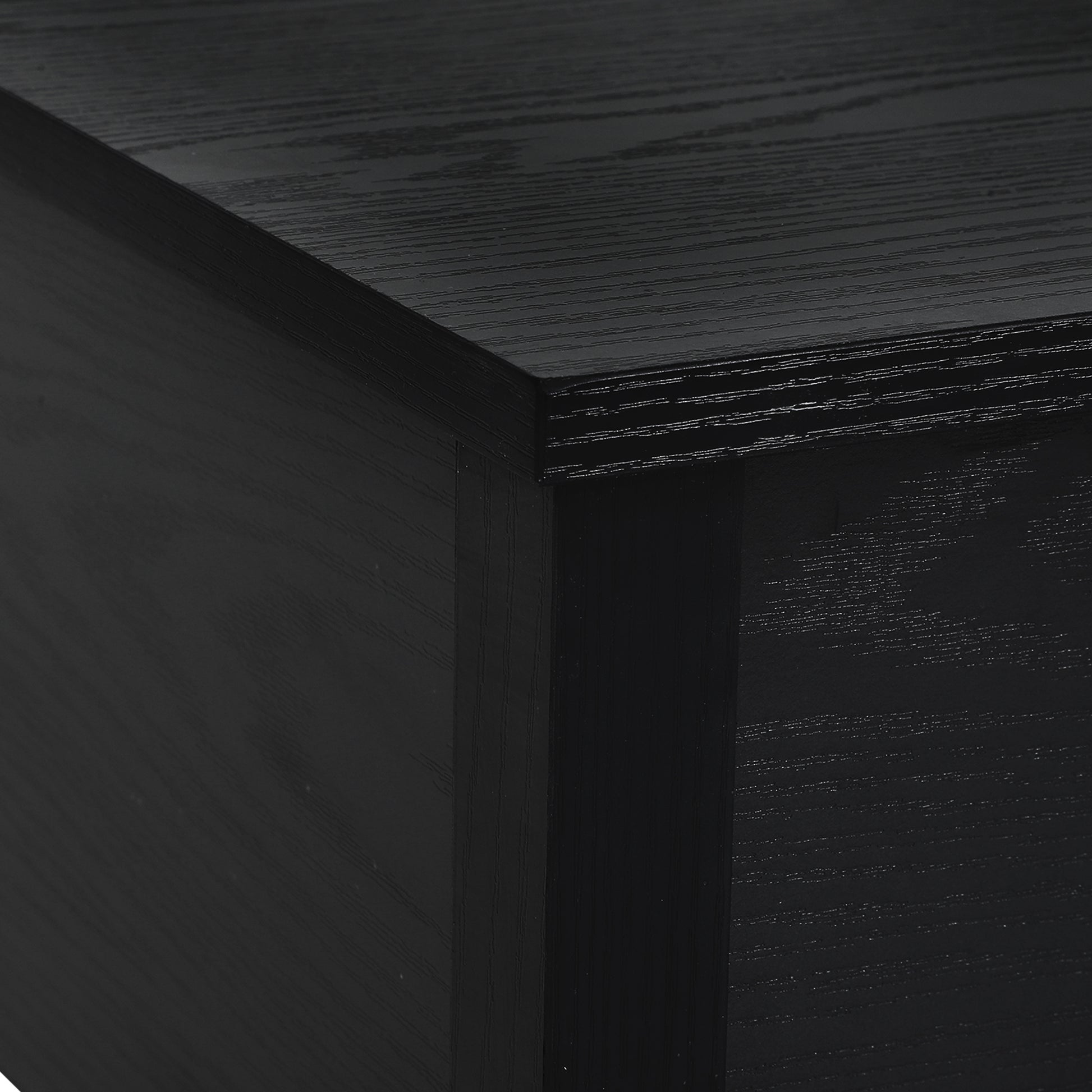 Closeup of a black wood veneer desk corner with visible grain texture