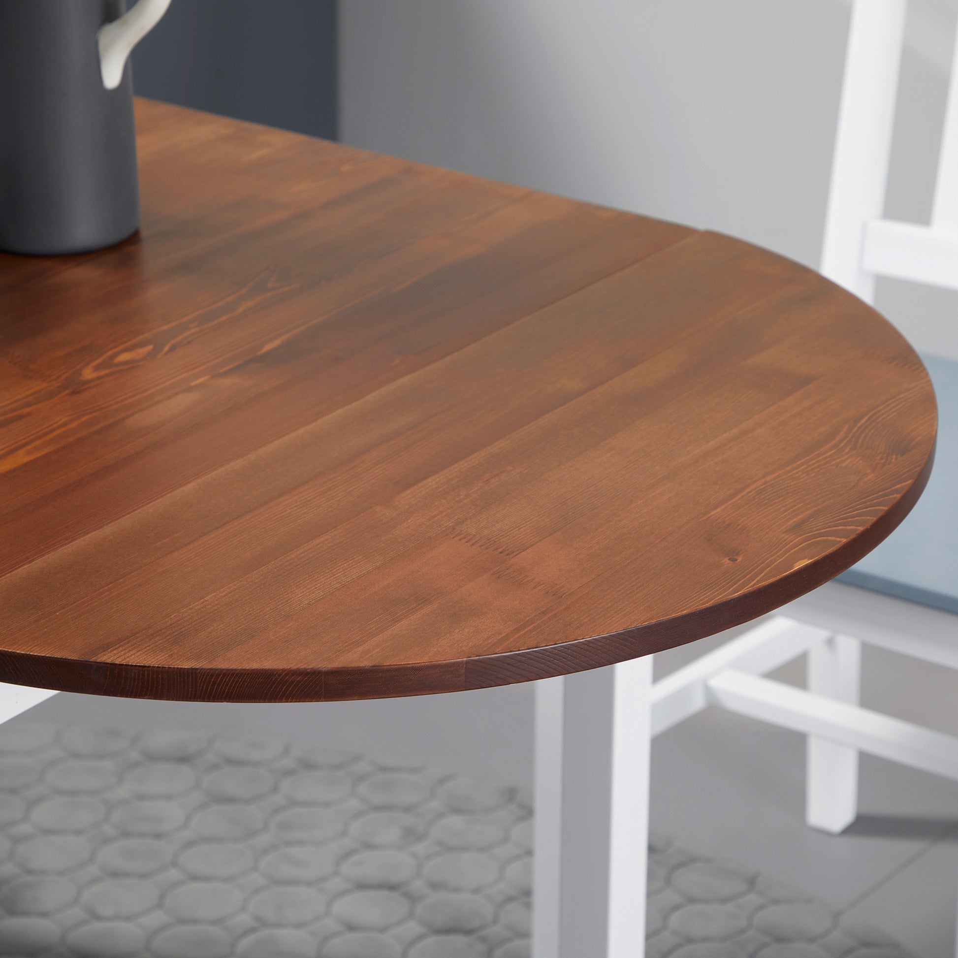 Round dining table with rich brown wood finish and white legs