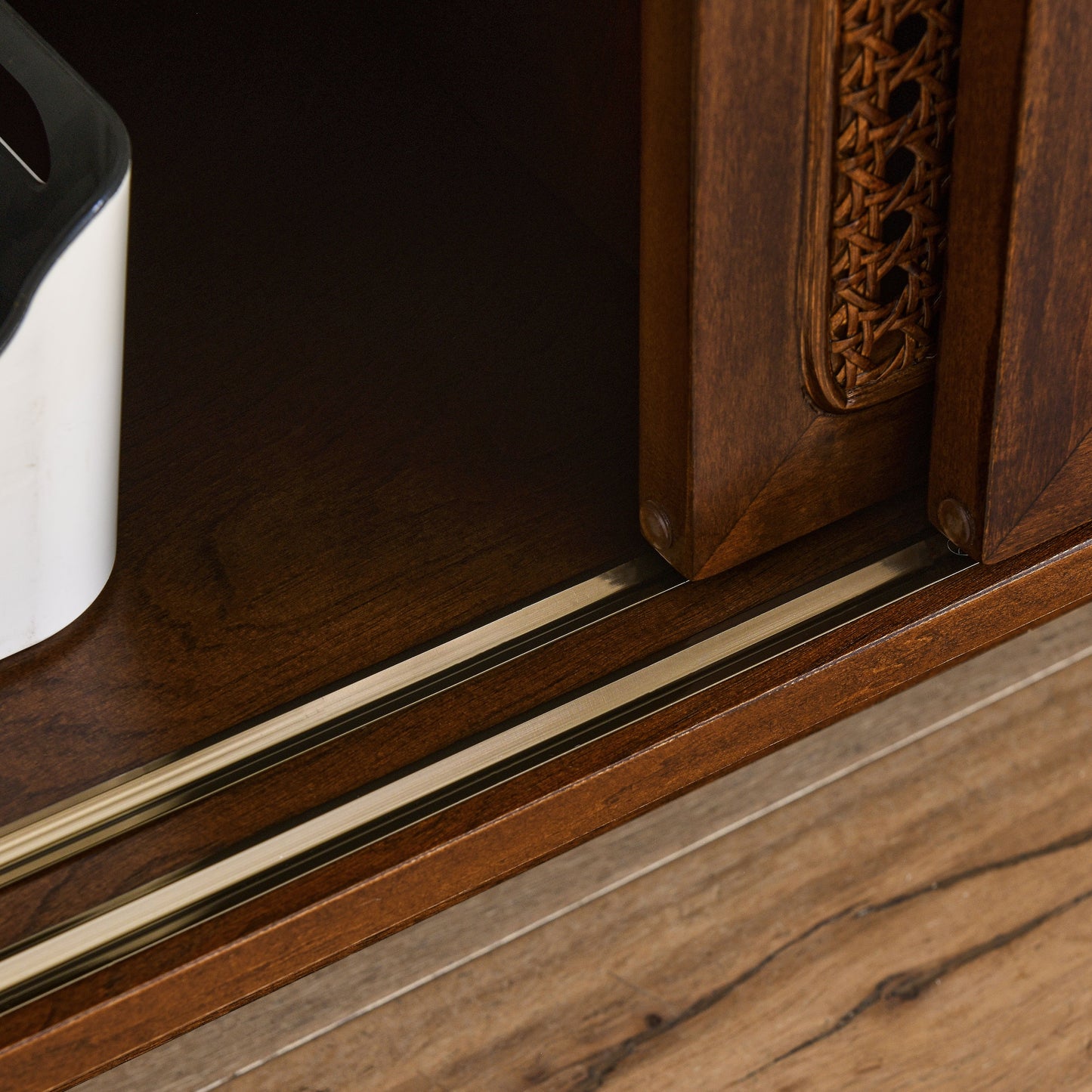 Closeup of dark wood furniture with cane inlay and metal drawer slides