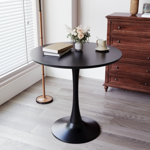 Black round tulip dining table with pedestal base featuring books and vase