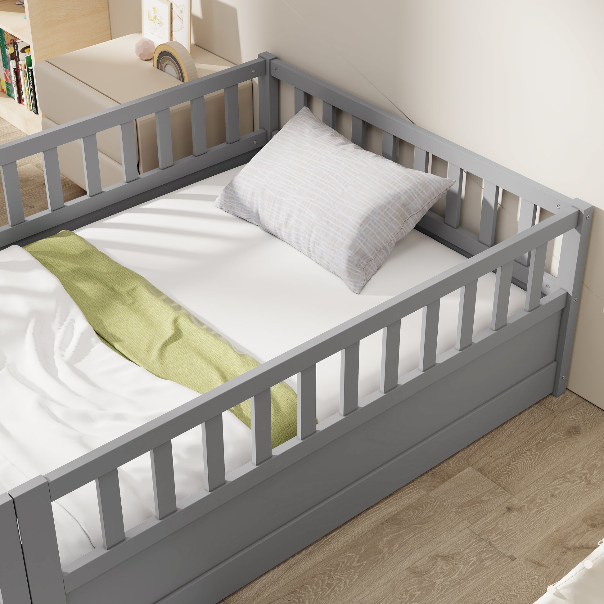 Gray wooden toddler bed with safety rails white mattress and a patterned pillow