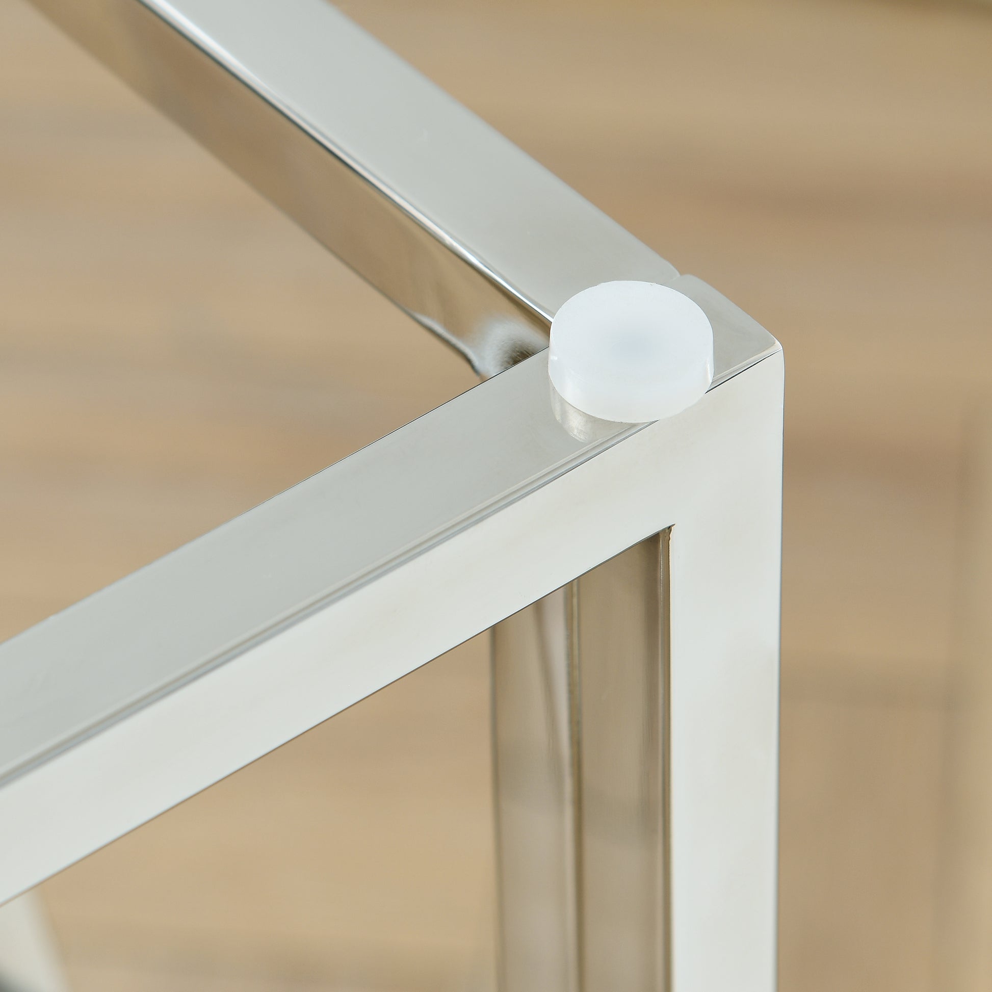 Polished silver metal frame corner with white floor protector cap on light wood floor