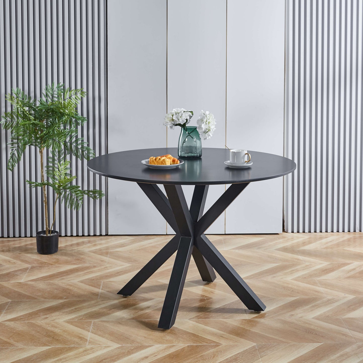 Round dark gray dining table with black pedestal base set for coffee and pastries