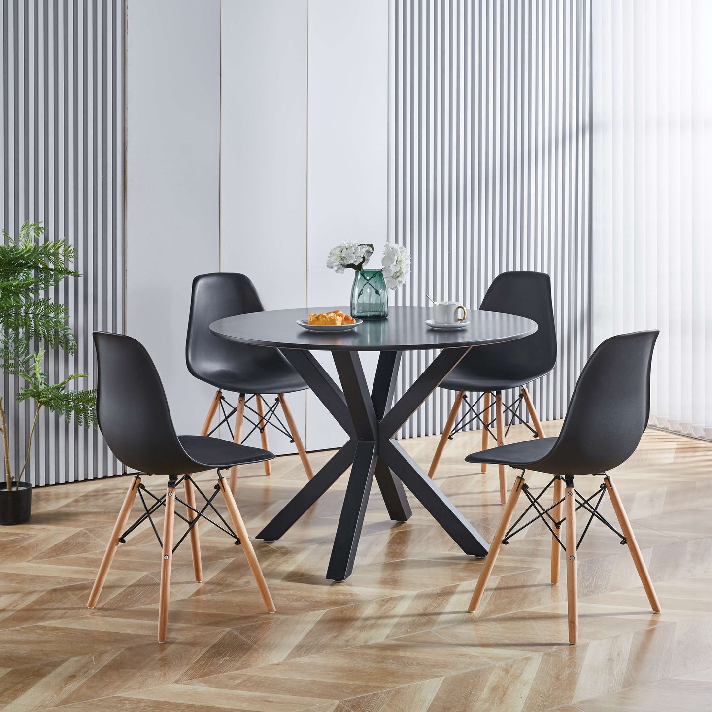 Round black dining table with four black chairs and wooden legs perfect for small spaces