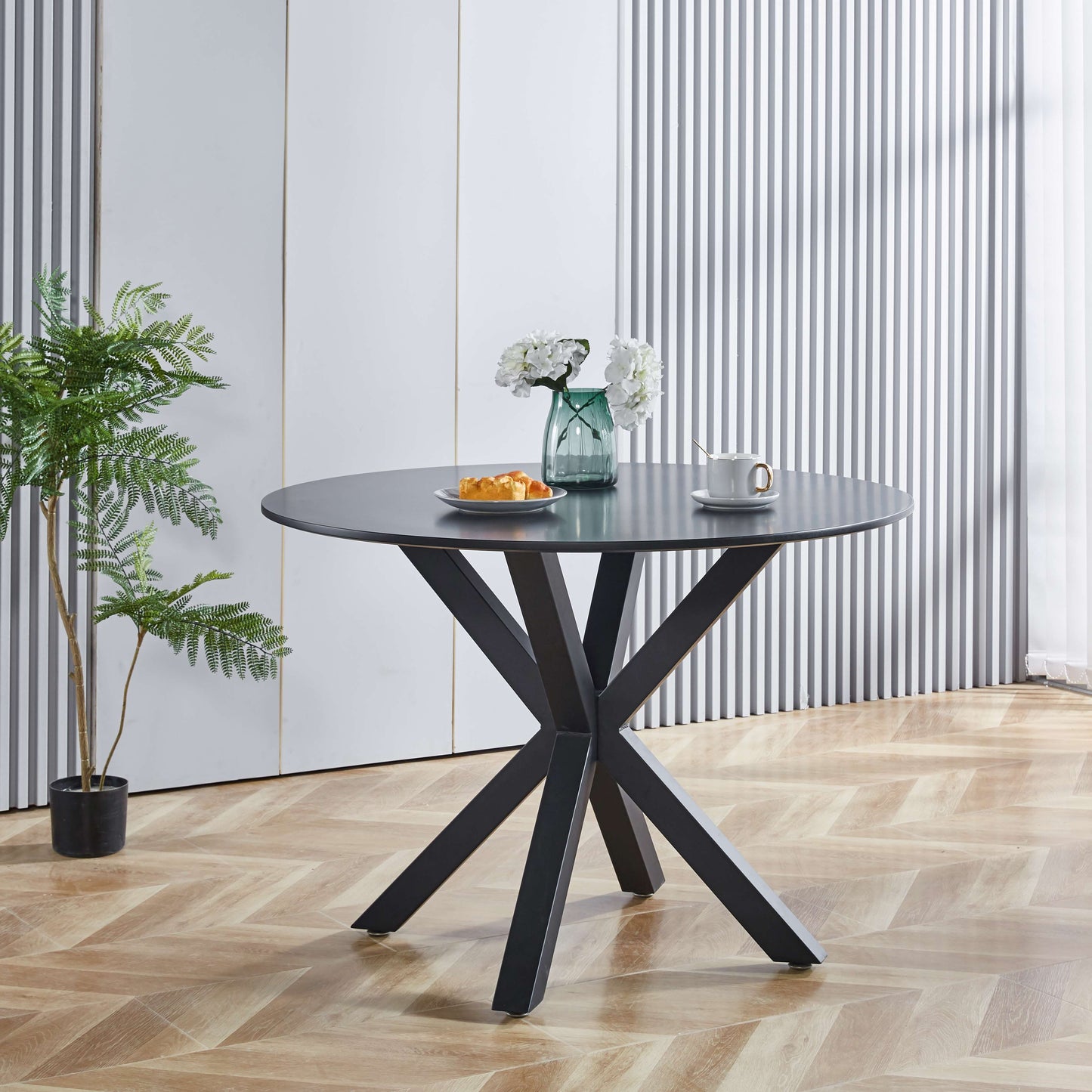 Round dark gray dining table with modern black metal crisscross base