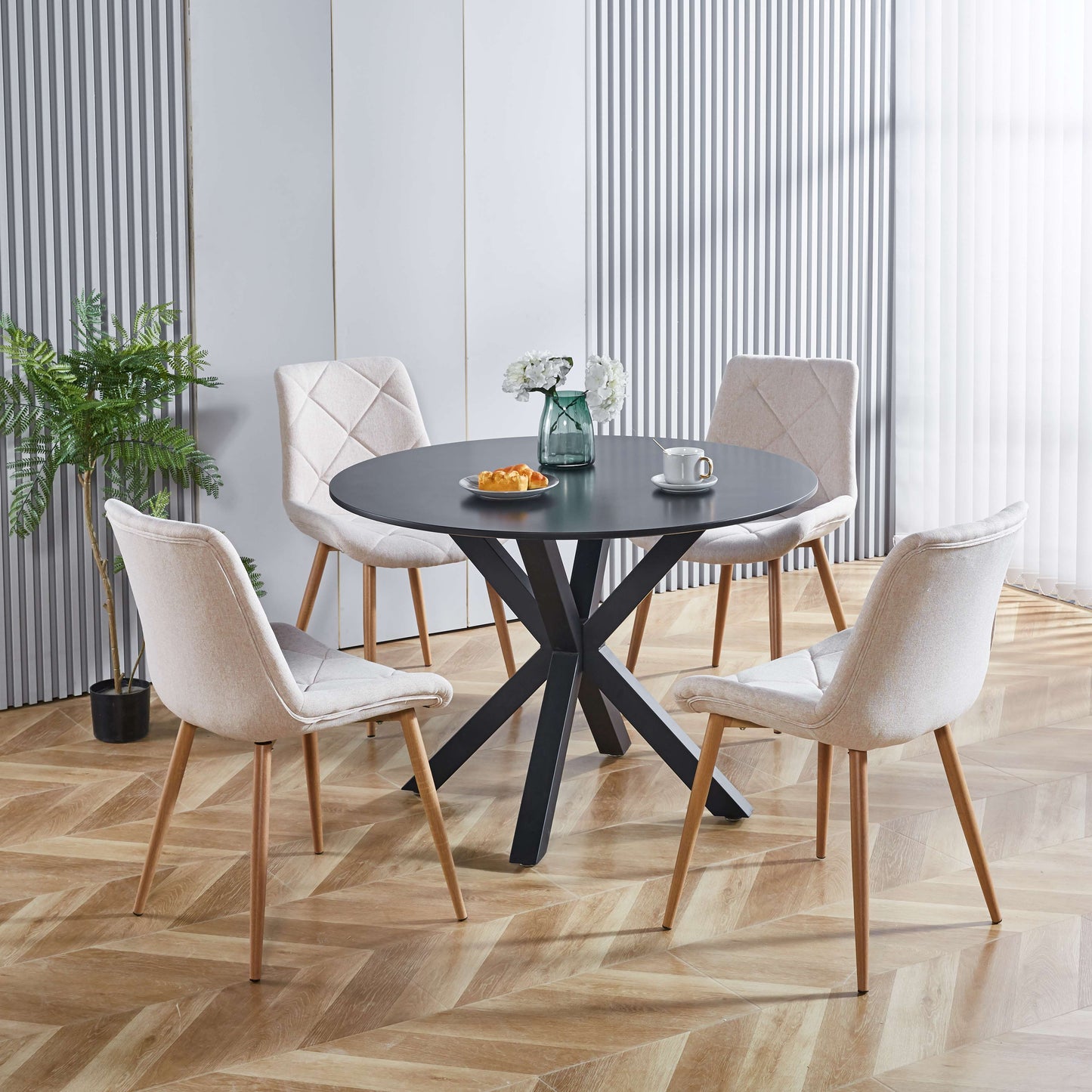 Round black dining table with four light beige upholstered chairs in a modern dining room