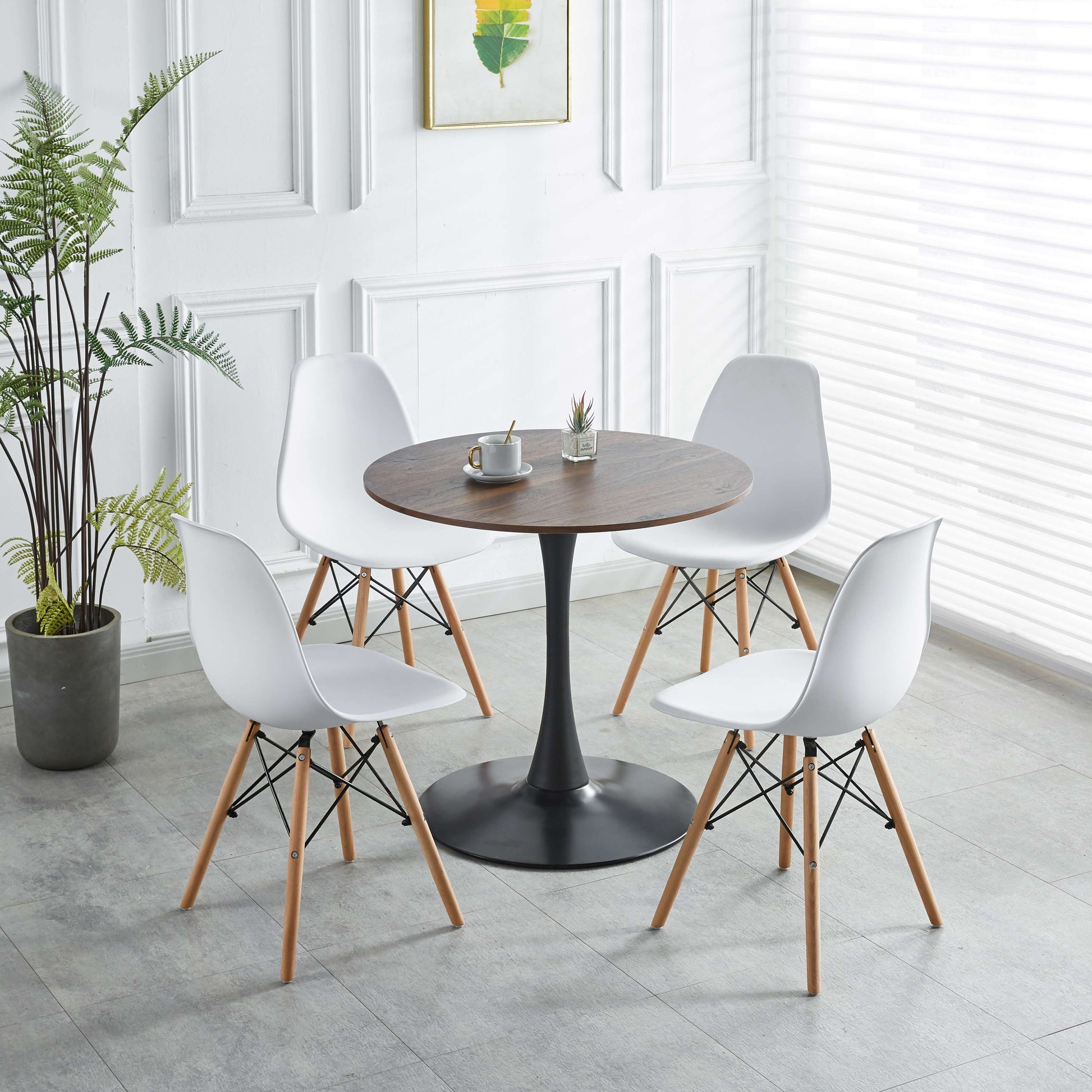 Four white dining chairs with wooden legs around a round walnut table for modern dining