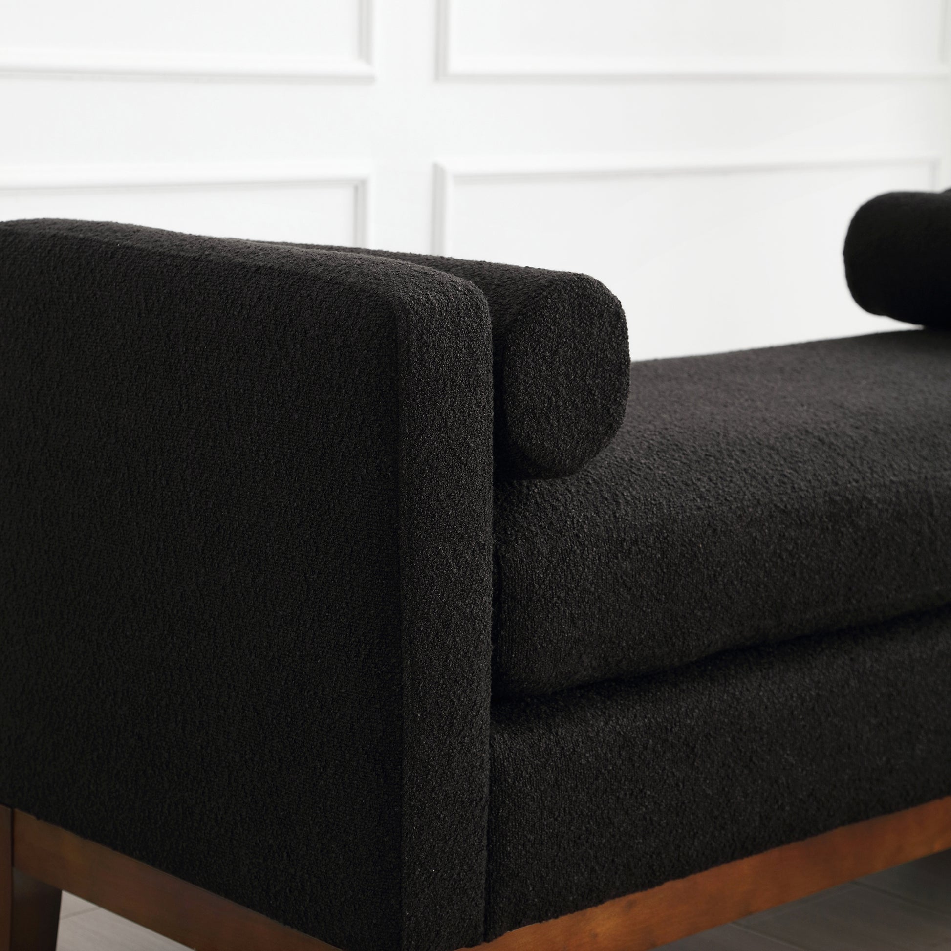 Black boucle accent chair with wooden legs and bolster pillow
