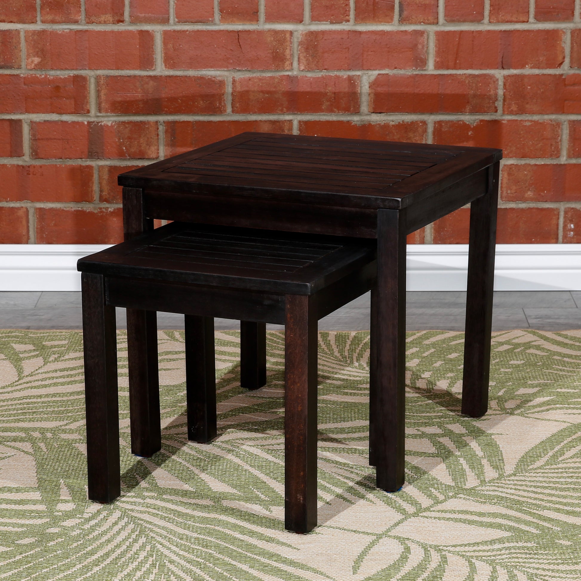 Dark wood nesting tables with slatted tops displayed on a tropical rug