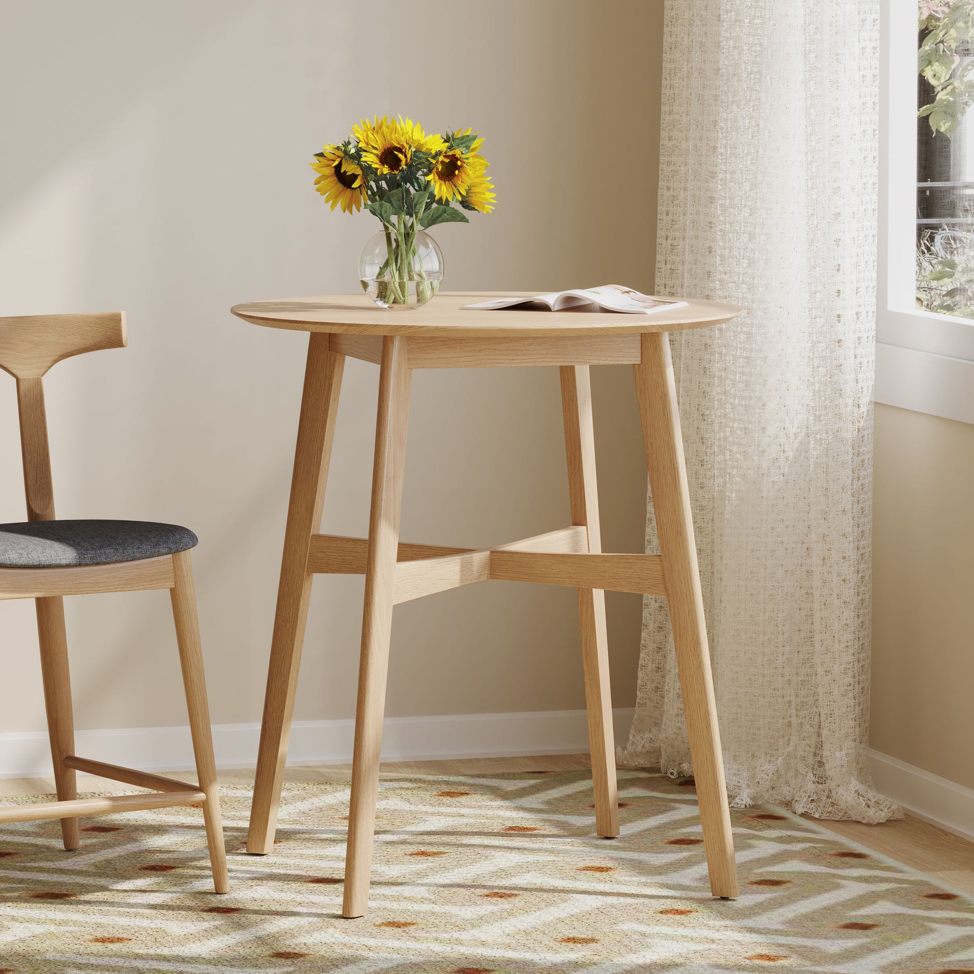 Round light oak wood pub table with a magazine and sunflowers