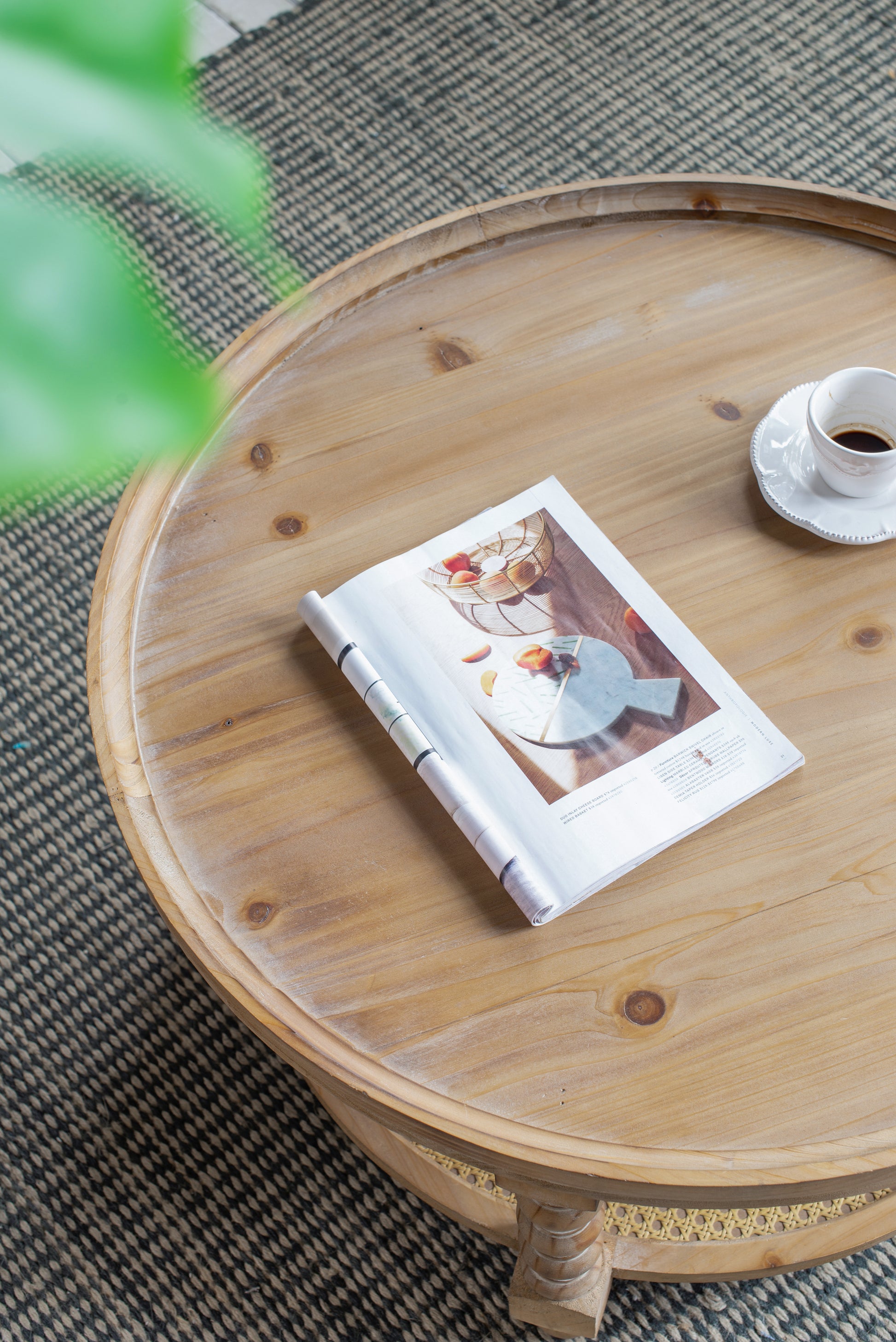 Round natural wood coffee table with magazine and espresso cup