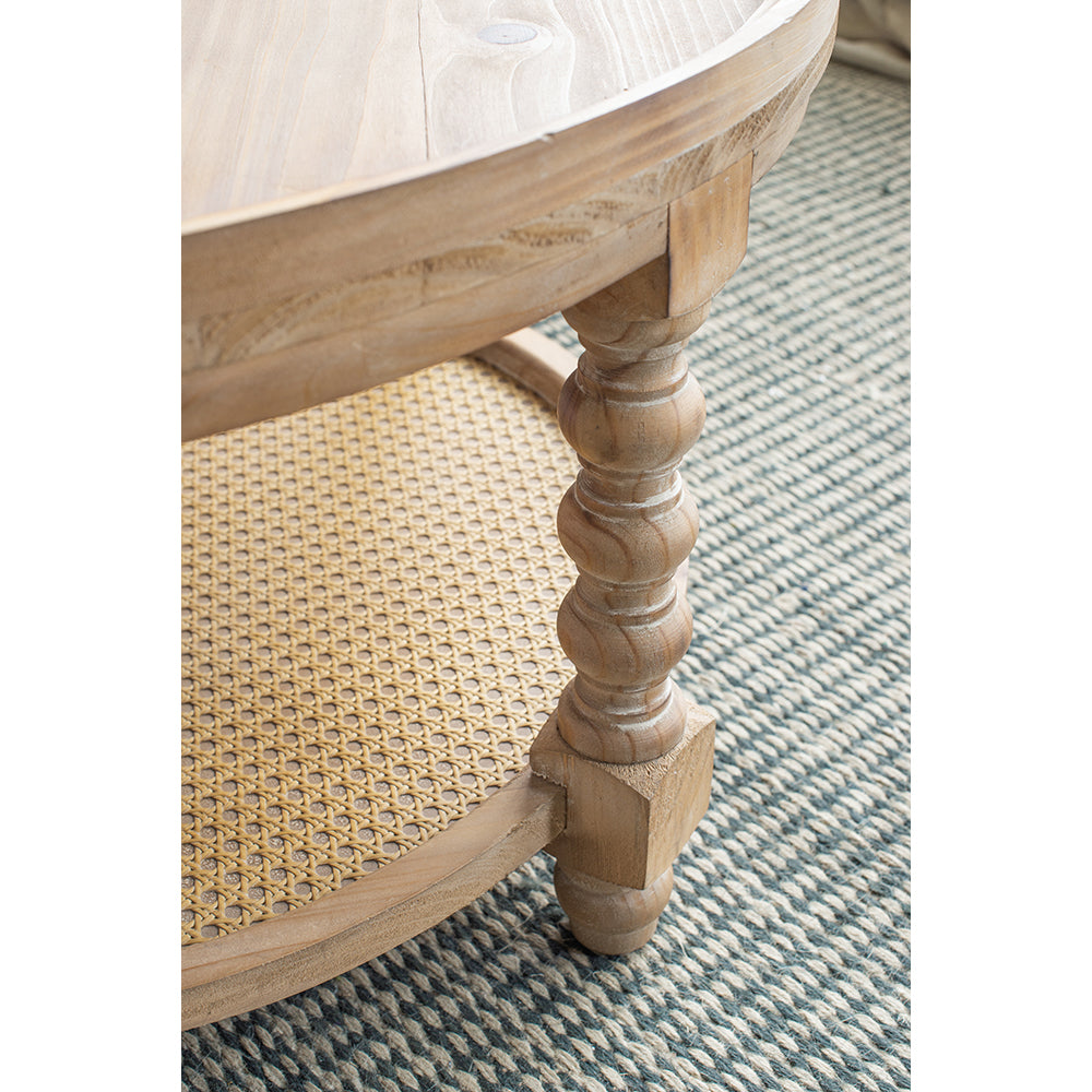 Detail of a light wood oval coffee table with cane shelf and turned leg