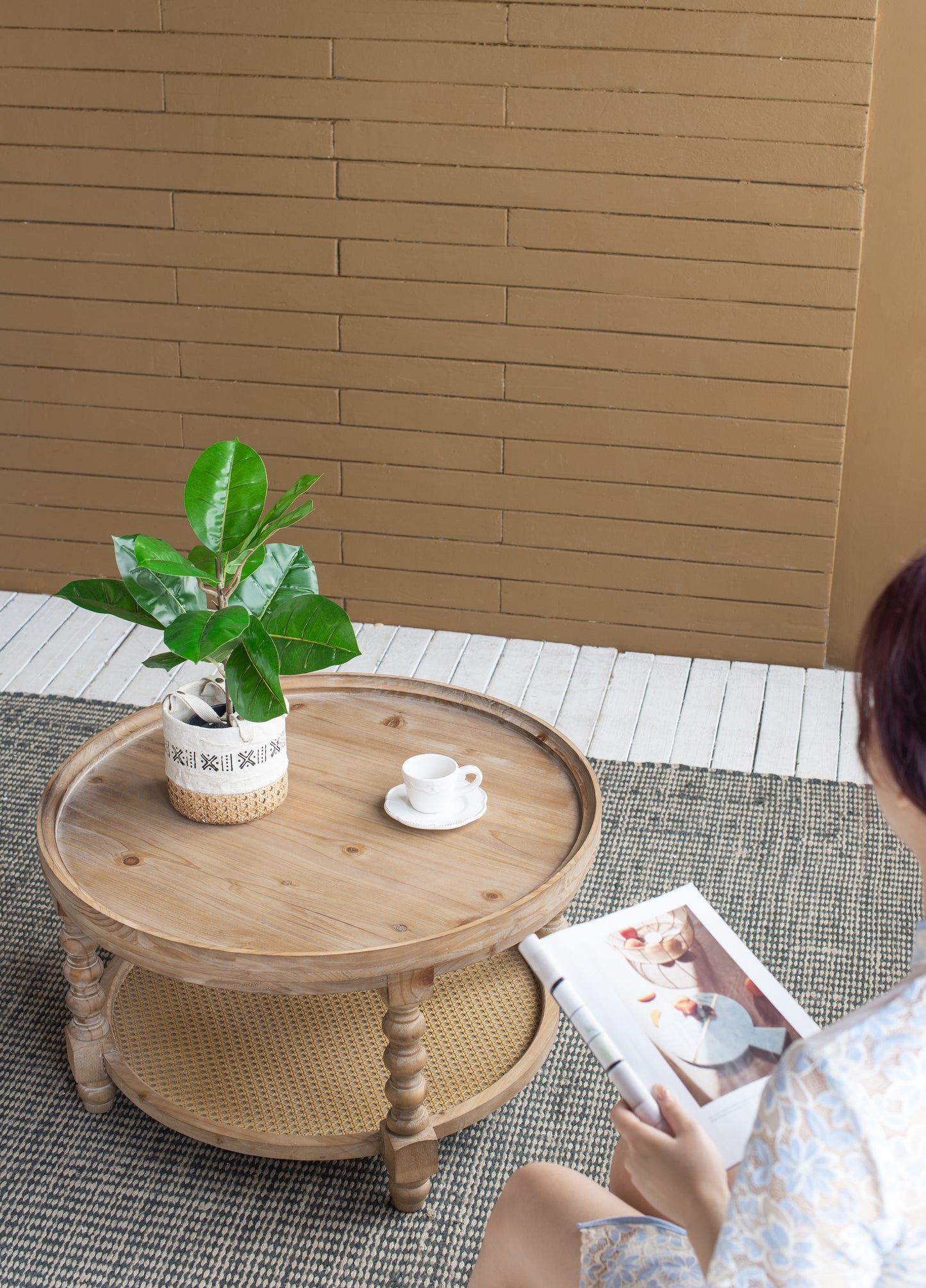 Round wooden coffee table with woven shelf and plant