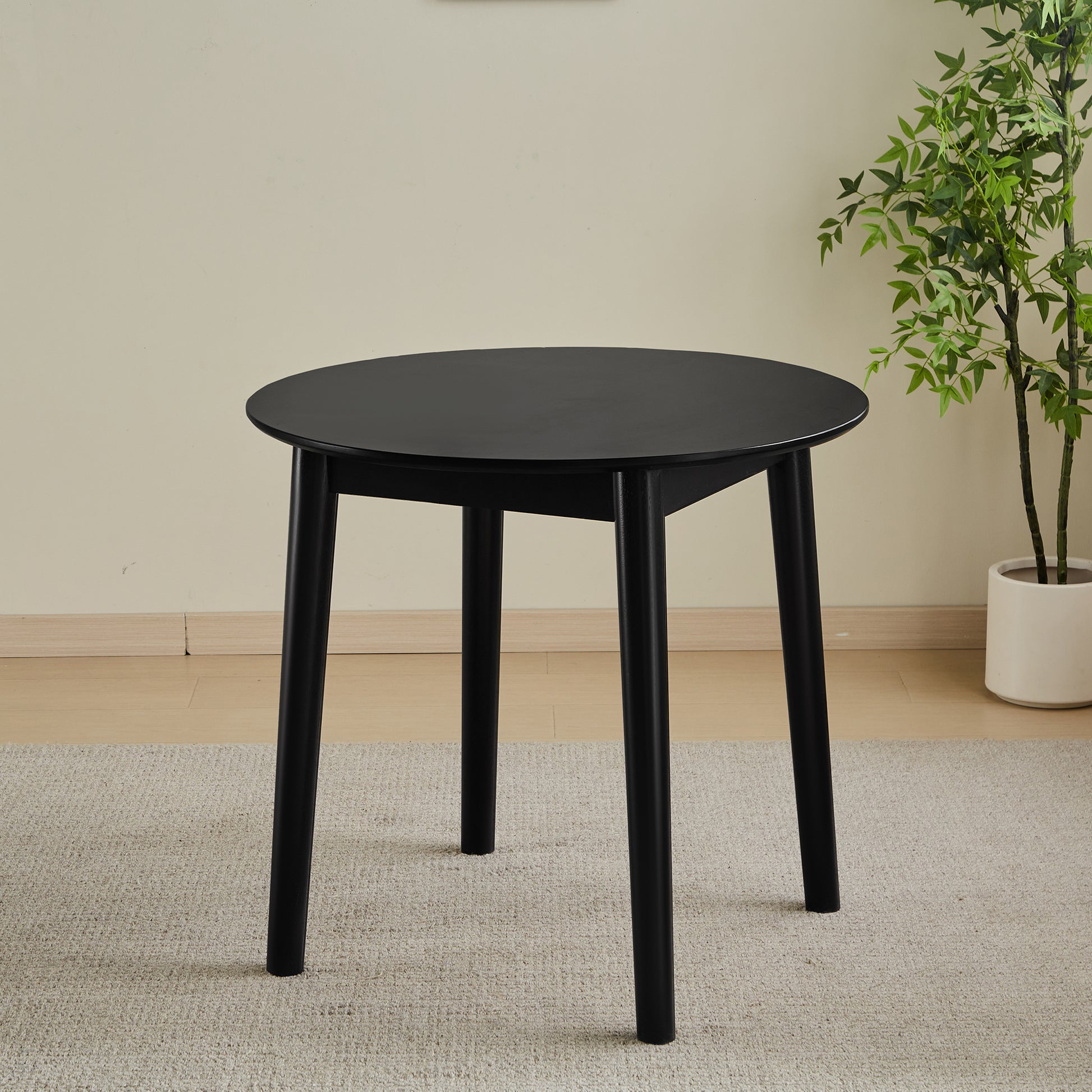 Black round dining table with tapered legs