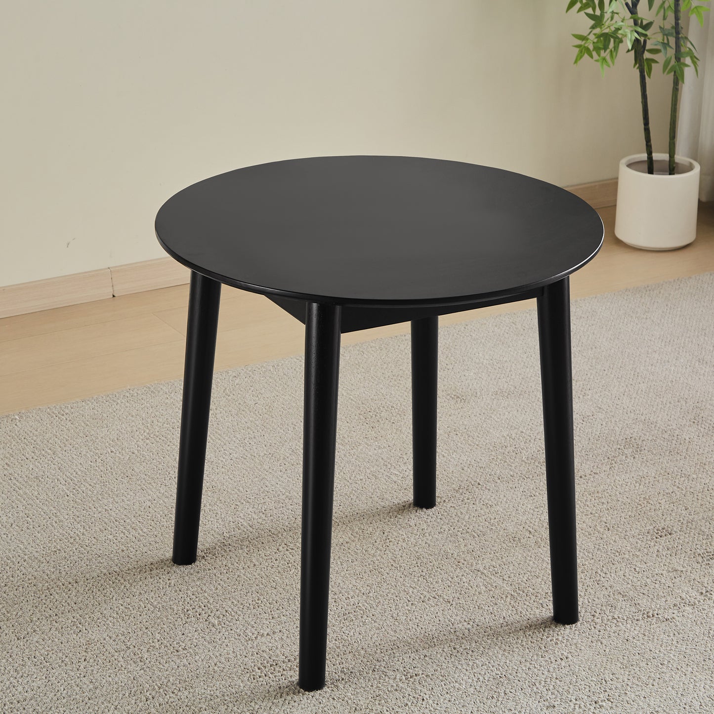 Black round wooden coffee table with four tapered legs