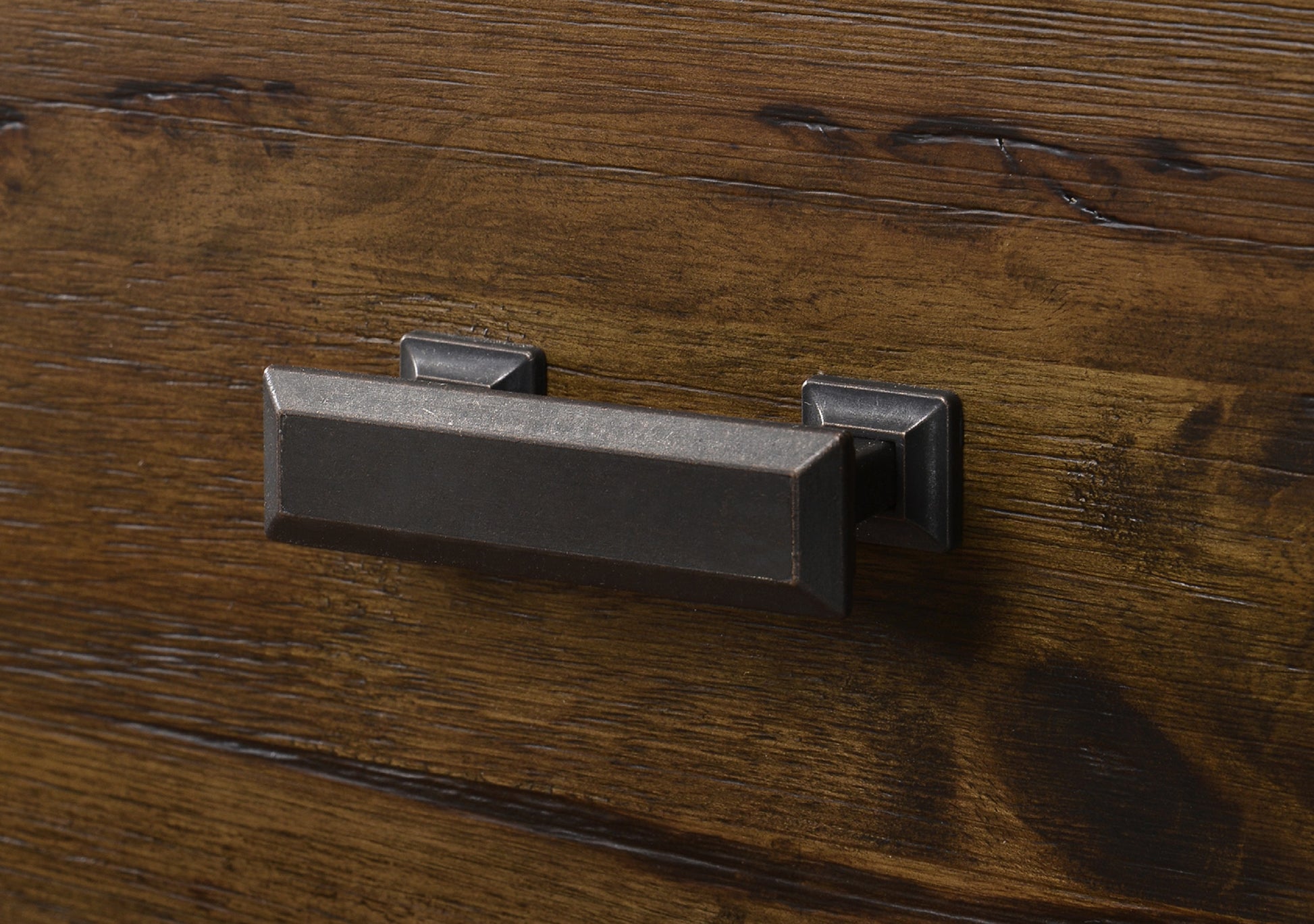 Rectangular brushed bronze cabinet pull on dark wood grain drawer