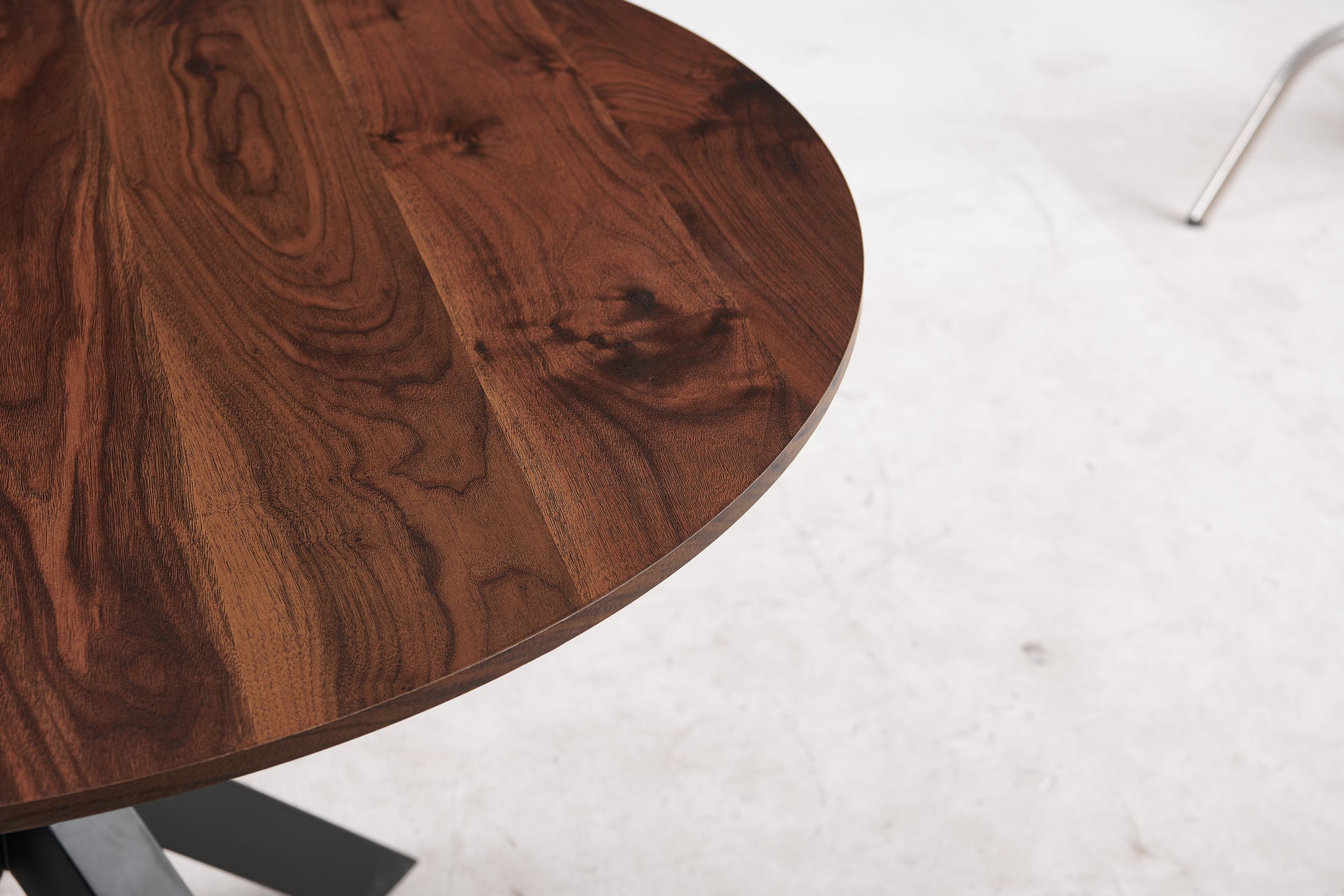 Closeup of a round walnut wood dining table with a dark brown grain pattern