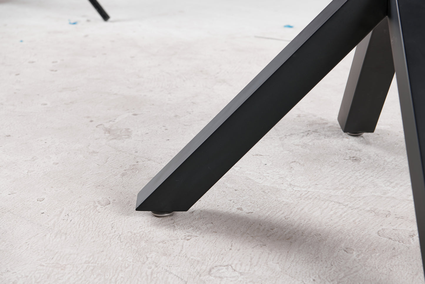 Black metal table leg with adjustable foot on textured floor