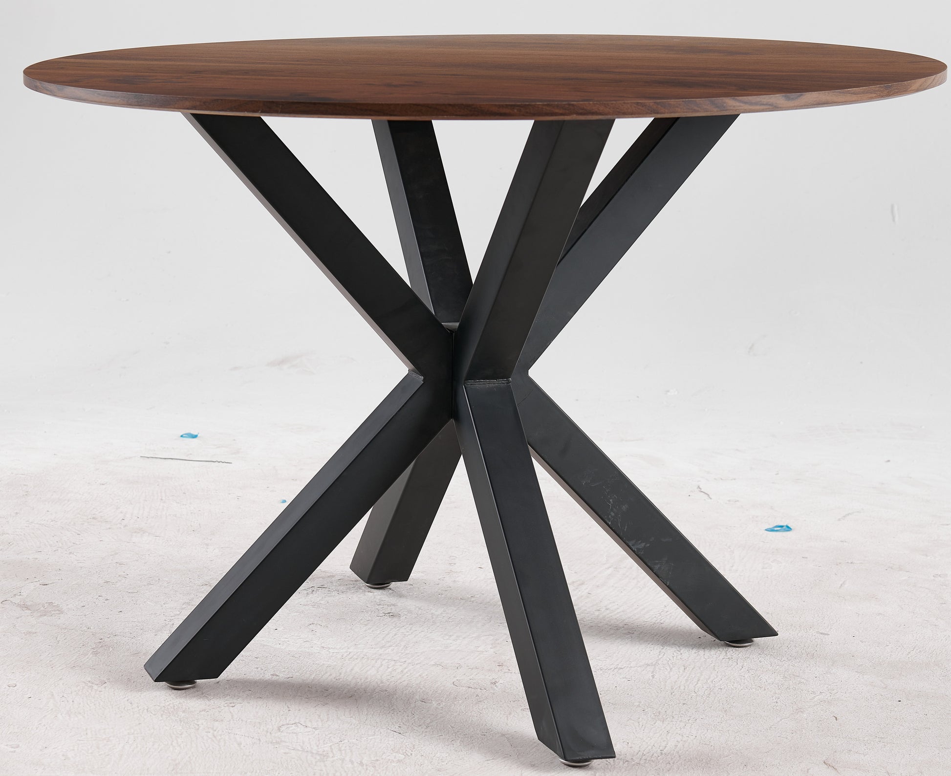 Round walnut dining table with black metal spider base