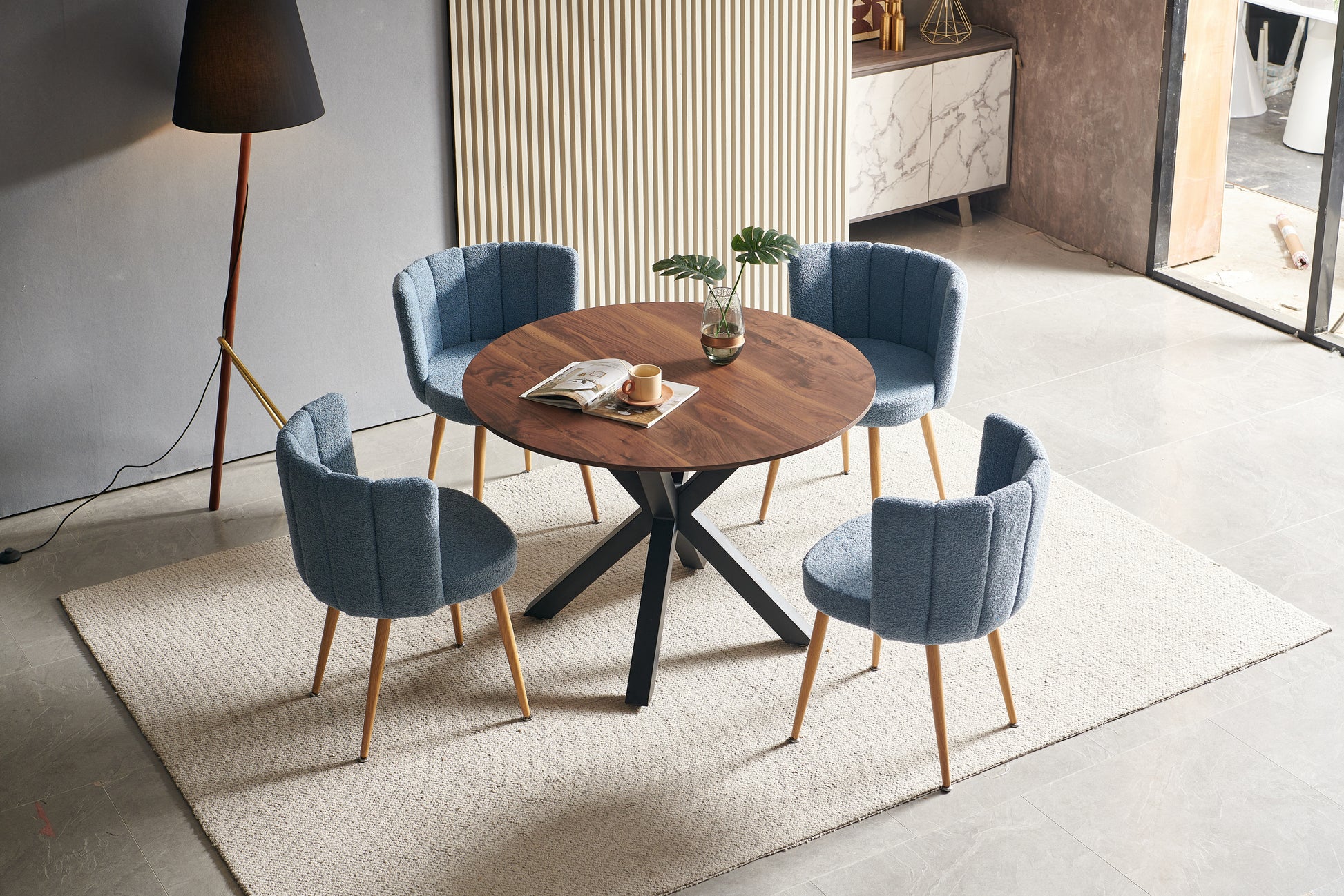 Round wood dining table with four blue boucle chairs