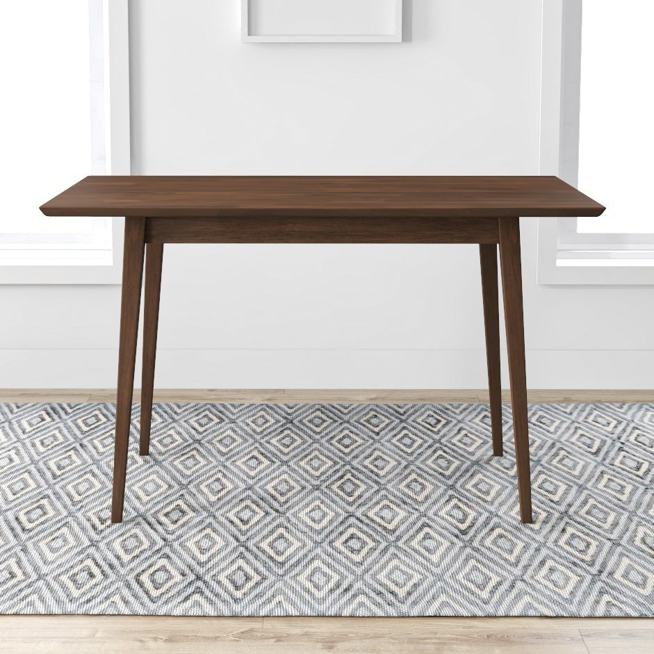 Dark brown wooden dining table with tapered legs on a geometric rug
