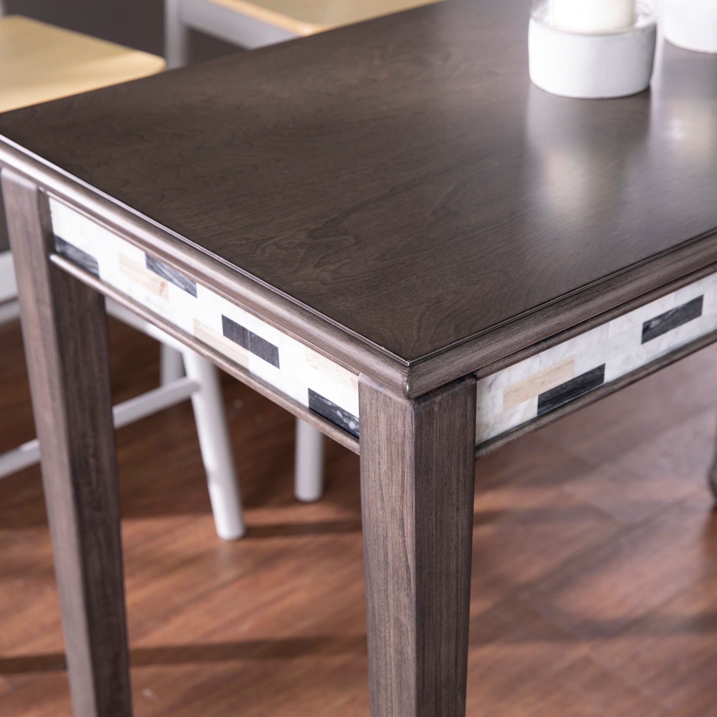 Dark wood dining table with inlaid geometric stone mosaic on apron