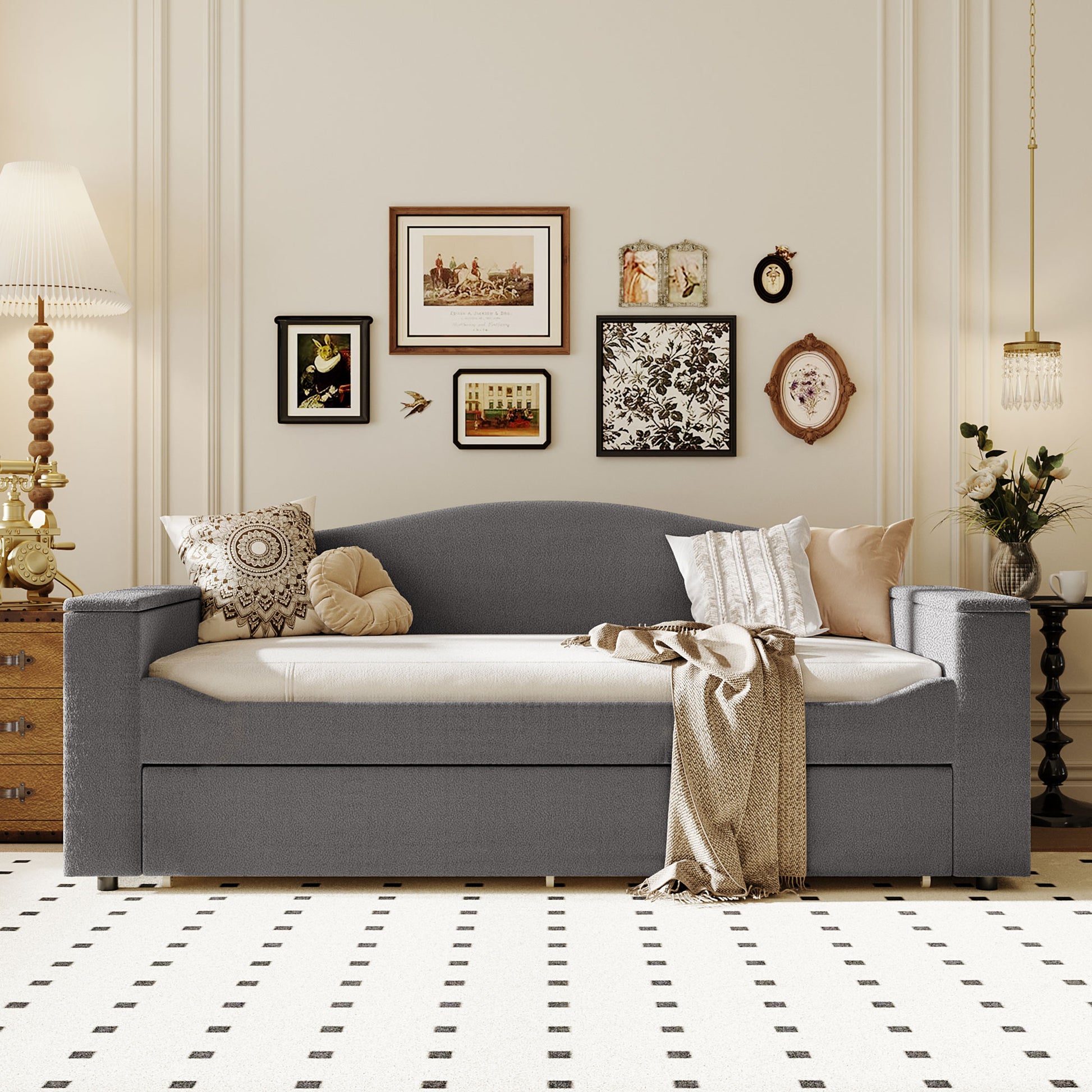 Grey upholstered daybed with tufted pillows and a throw blanket