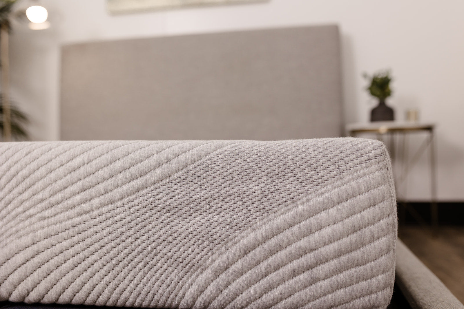 Close up of a light gray quilted mattress with diagonal stitching detail