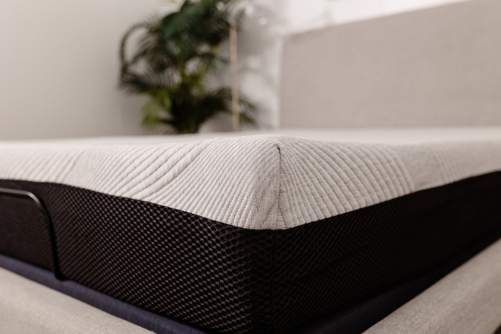 Closeup of a grey textured mattress with a black mesh side panel