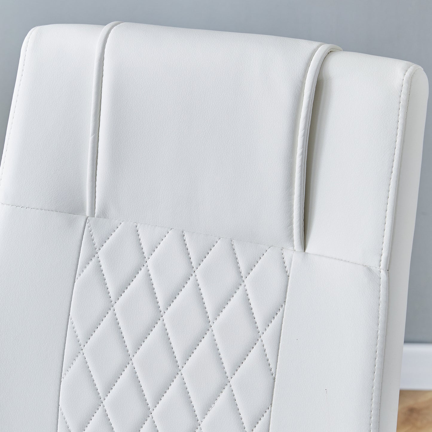 Closeup of white faux leather chair back with diamond stitching