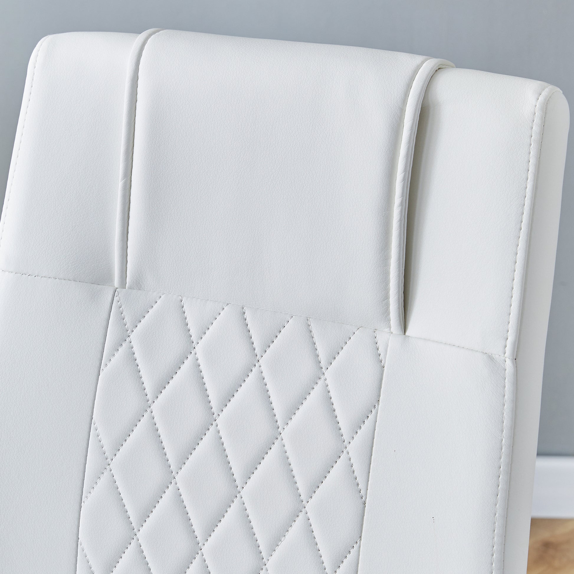 Closeup of white faux leather chair back with diamond stitching