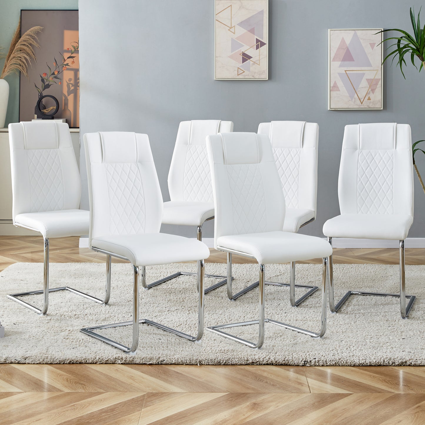 White faux leather dining chairs with diamondstitched backs and chrome sled legs