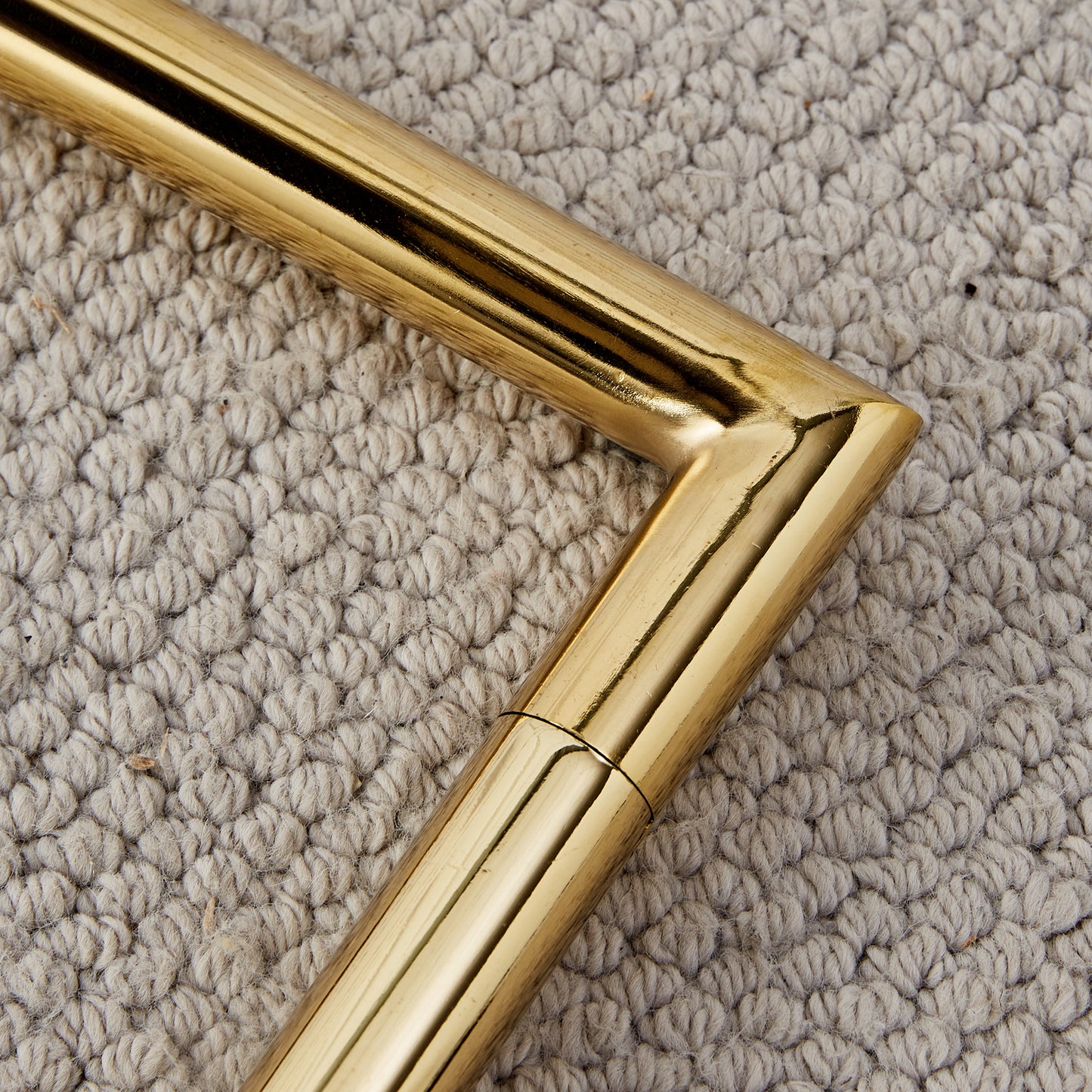 Polished brass table leg detail on textured rug