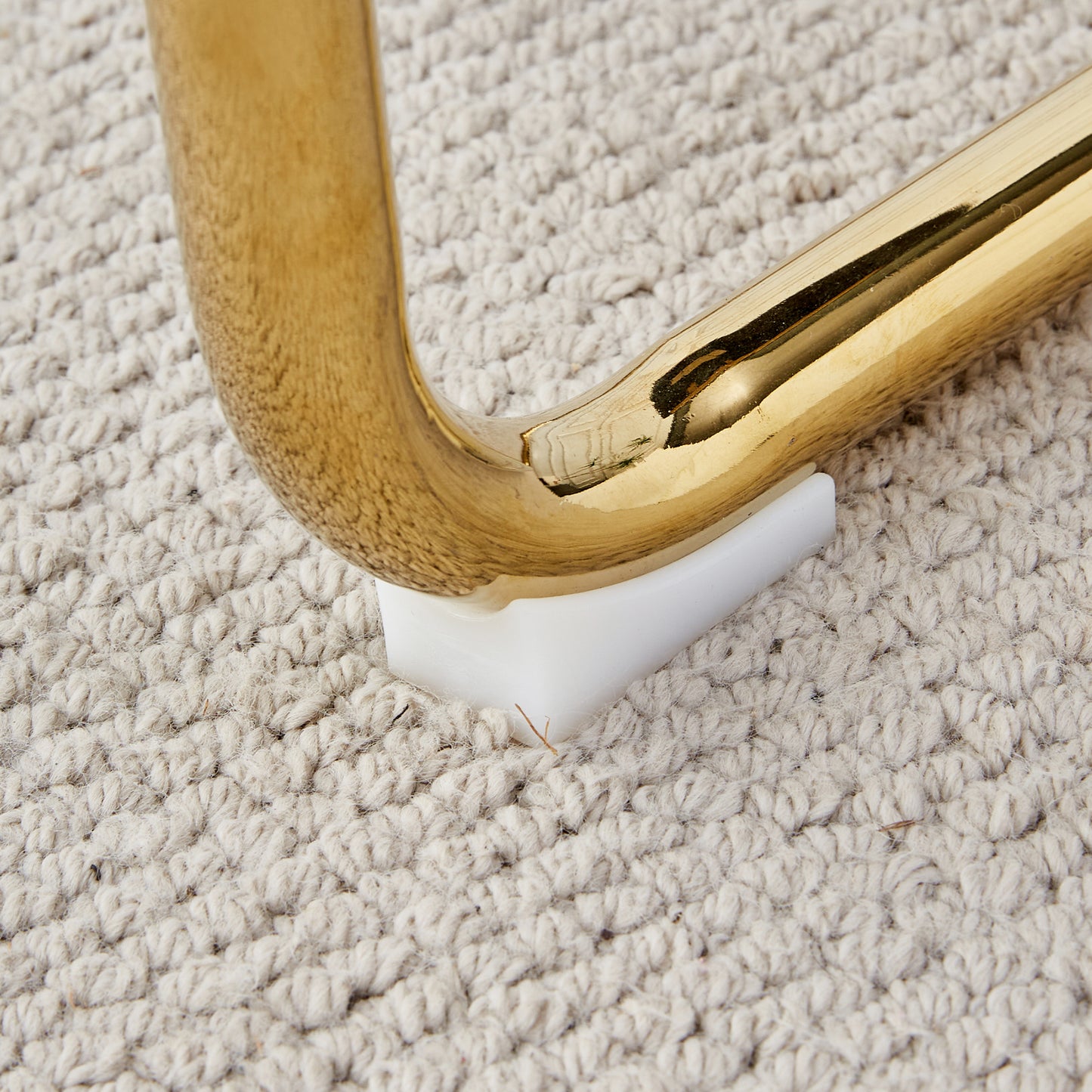 Polished brass furniture leg rest on cream carpet