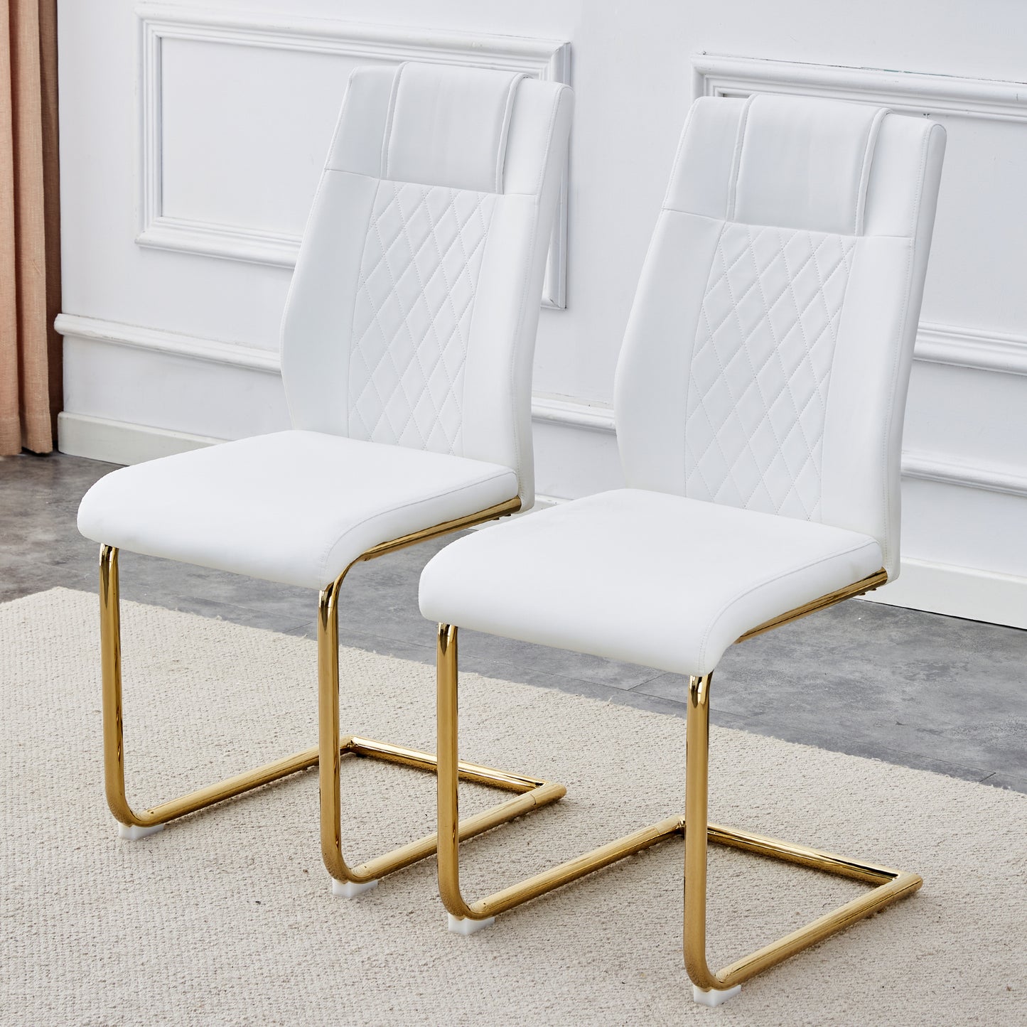 Two white faux leather dining chairs with diamond stitching and gold sled legs