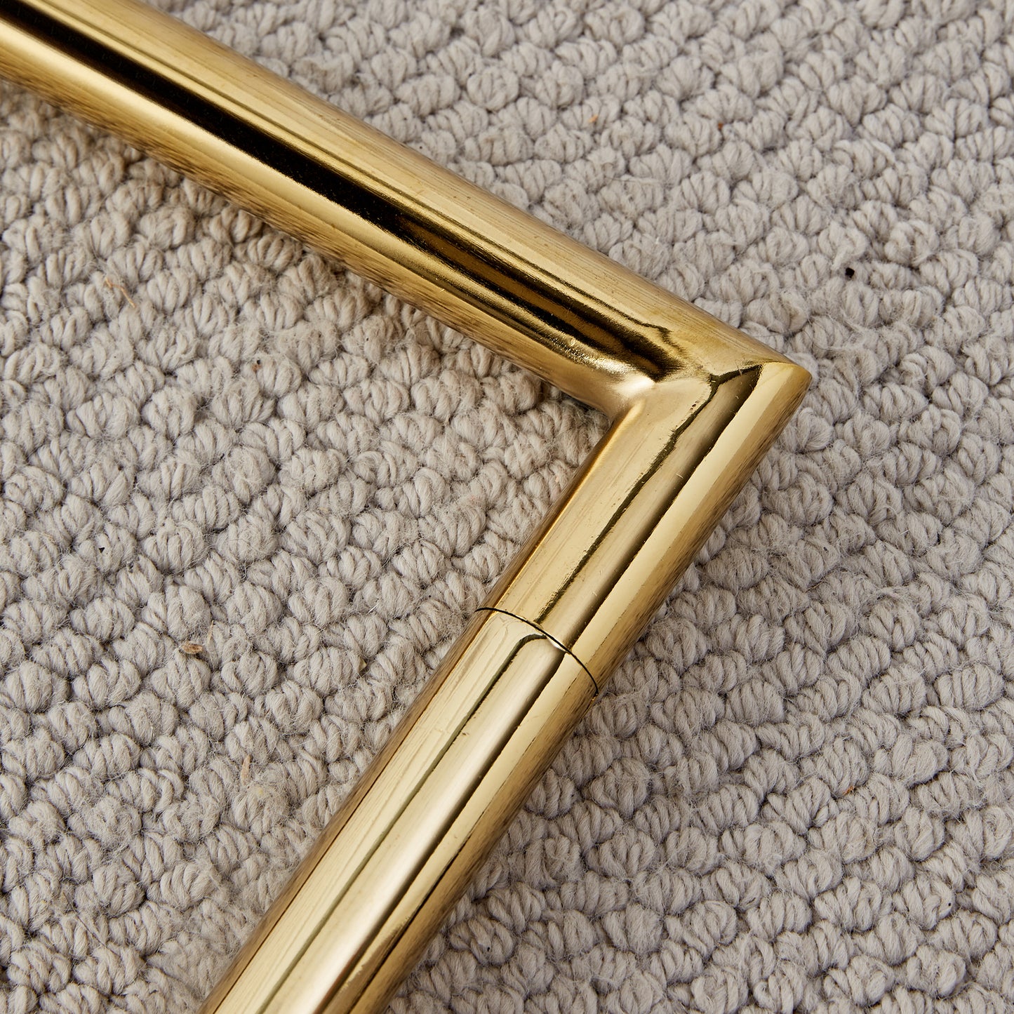Polished brass angled accent on a textured beige rug