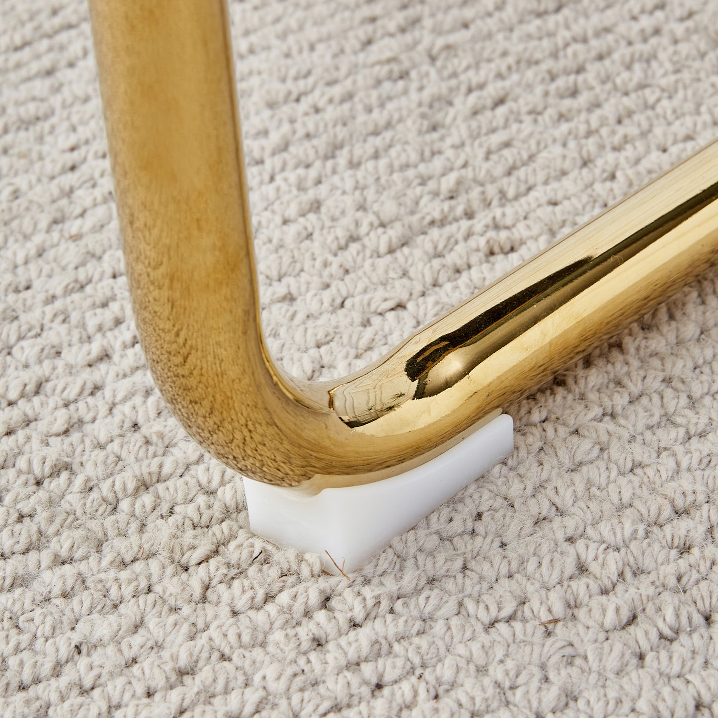 Shiny brass furniture leg detail on textured rug